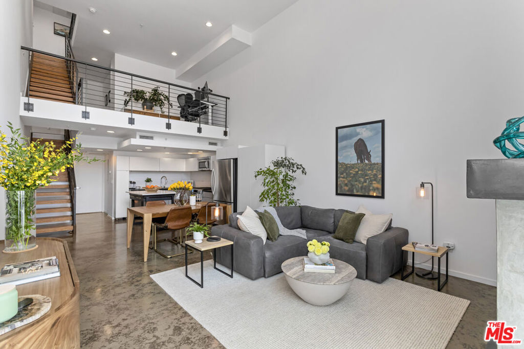 Enjoy modern loft living in this thoughtfully designed townhome by Jonathan Davis of Davis Studio A & D, formerly with Frank Gehry and Associates. Carefully crafted to optimize space and light, this home features double height windows, open living spaces, and soaring 20 foot ceilings. The living area fireplace and the curated materials of steel, wood, and polished concrete synergistically create a warm and modern mood. The prime south facing location fills the home with light and provides wonderful tree top views. An inviting front patio welcomes you to the open concept living, dining, and kitchen areas. The second level is an open loft flex space, and could be used as a den/bedroom/office. The primary suite includes a wall of generous storage and closets, a zen bathroom, clerestory windows, a reading/sitting area and it opens to a spacious balcony, perfect for your morning coffee or evening glass of your favorite beverage. Conveniences and upgrades include in-unit laundry, Phillips Hue Color Changing LED Lights for all of the recessed lighting, and a newer ultra-reflective roof system. Building amenities include EV chargers, additional storage, a large bike room, common area patio, guest parking, and earthquake insurance. Within minutes of Larchmont Village, and conveniently located near Koreatown, Hollywood, and Downtown, this architectural beauty offers the chance to truly savor contemporary LA living.