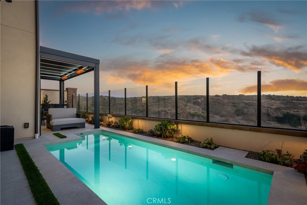 208 Canterbury in Irvine’s prestigious Sierra community by California Pacific Homes is a truly rare offering—one of the few homes in the city that boasts both a private pool and stunning views. Built in 2022, this two-story detached residence features 4 bedrooms, 4 bathrooms, and 2,548 sq ft of thoughtfully designed living space on a 3,154 sq ft lot, with nearly $400,000 in upgrades. The gourmet kitchen impresses with an upgraded island countertop crafted from high-end materials, a modern backsplash, custom cabinetry with enhanced finishes, and top-tier appliances. The open floor plan showcases luxury vinyl flooring on the first floor, a dramatic floating staircase with integrated night lighting, and soaring ceilings accented by a statement chandelier. Every detail has been considered, from the indoor fire pit in the living room to whole-house Wi-Fi extensions and upgraded window coverings throughout. The resort-style backyard is a showstopper with a saltwater pool/spool system equipped with automated temperature control, LED lighting, automated circulation, filtration, and water level systems. The fully automated patio includes retractable screens, integrated lighting, two large-capacity infrared heaters, 220-volt outlets, and a wind sensor for convenience. Professionally landscaped with signature trees, porcelain tile yard surfaces, and large decorative planters, the outdoor space is designed for year-round enjoyment. The expanded driveway, architectural night lighting, and extended porcelain tile entryway enhance the curb appeal. The garage is equally functional and stylish with epoxy flooring, custom storage cabinets, a built-in shoe cabinet, an EV charging station, and an interior camera. Energy efficiency is maximized with 27 solar panels providing 10 kW capacity. Upgraded bathrooms with modern shower booths and finishes add to the luxurious feel of the home. Zoned for top-rated Irvine Unified schools—Loma Ridge Elementary, Jeffrey Trail Middle, and Portola High—this property features premium upgrades, cutting-edge energy-efficient systems, and unparalleled outdoor living in one of Irvine’s most desirable master-planned communities.