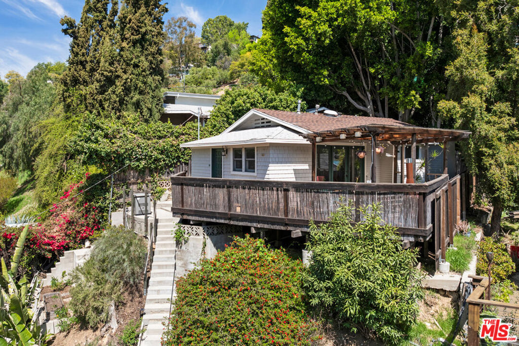 Perched on a hillside in Mt. Washington, this 1923 cottage is a peaceful escape with treehouse vibes, expansive deck, and picturesque canyon views. Step inside and you're wrapped in privacy and quiet, high above the street. The sunny interior feels like a creative haven, full of character details like painted brick, beamed ceilings, built-ins, and wood-look flooring. The kitchen has been refreshed, and indoor-outdoor flow is easy, with the living room extending to a deck that's perfect for morning coffee, dinner with friends, or relaxed evenings under the trees. The bedroom is serene, and the bath has been recently updated. Lush terraced landscaping and drought-tolerant flora set the scene, and a private patio in back adds more outdoor space. Amenities include central AC and laundry. Distinctly Mt. Washington, the home puts you close to some of LA's best hiking trails and a great lineup of coffee and dining spots along Figueroa in nearby Highland Park.