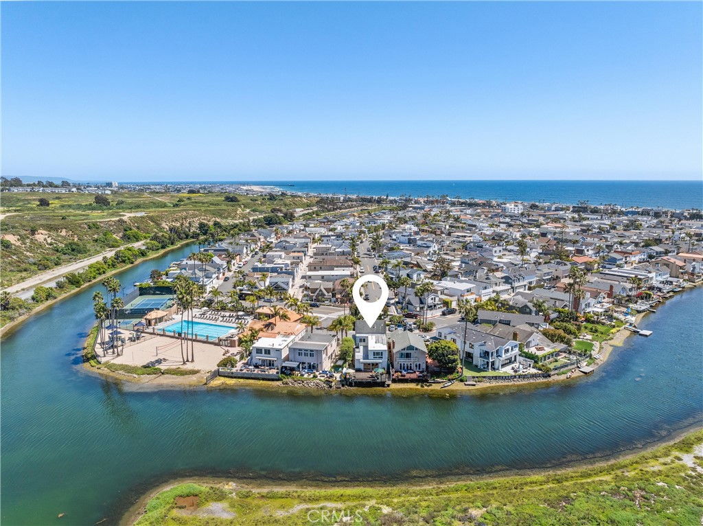 Premiere waterfront location with endless views! This four-bedroom, three-bathroom home is ideally situated in the highly sought-after Canal Circle in Newport Shores. The spacious kitchen features quartz counters and generous counter space. Flowing seamlessly from the kitchen, the dining area and living room both offer access to a canal-facing deck, perfect for enjoying the serene waterfront views. The primary suite includes vaulted ceilings, a loft area, a walk-in closet, and an updated bath. The three other bedrooms are spacious and offer open beamed ceilings, and ample closet space. This home also features updated stone-clad bathrooms, French doors, recessed lighting, two cozy fireplaces, and the comfort of air conditioning. The two-car garage includes storage as well as an opportunity for additional exterior parking. Enjoy beach living and all the amenities of the Newport Shores Community Association - pool, tennis, pickleball, volleyball, basketball, playground, and barbecue area.