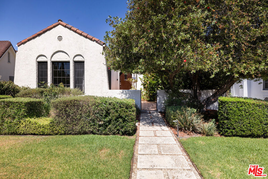 Redefine the art of living and entertaining at this beautifully detailed and enviably private Spanish-style home in the heart of LA's Miracle Mile neighborhood. Characterized by a host of authentic architectural details and carefully curated upgrades, the gracious residence was built in 1925 and stands proudly as a testament to timeless design. A large, gently sloping lawn graces the front of the single-level residence, which embraces all with a gated front patio distinguished by Spanish tile and mature plantings. Indoors, an abundance of multi-paned windows and French doors welcomes natural light, illuminating an elegant fireplace-warmed living room with barrel ceiling, and a spacious dining room with a wall of windows. Romantic archways, hardwood and cork flooring, solid wood doors with glass handles, coved ceilings and custom window treatments lend an air of subtle sophistication to the home. Open to the dining room, a remodeled kitchen impresses with stained-wood Shaker cabinetry with glass uppers, a colorful full tile backsplash, solid-surface countertops, outdoor access, stainless steel appliances, and a convenient laundry closet with stacked washer and dryer. A large peninsula is perfect for casual meals and serving up small bites during memorable gatherings with friends and loved ones. Approximately 1,824 square feet, the move-in-ready home hosts three bedrooms and two baths, with one bath offering period-perfect finishes and the other displaying upgraded tile and fixtures. Bedrooms offer comfort, privacy and serene garden views, while a finished detached two-car garage can easily become an ADU, office or studio. With a newer deck, intimate patios and gorgeous landscaping, the private backyard presents an outstanding setting for cocktail parties, barbecues, and easy relaxation by sun and starlight. This sanctuary-style ambiance of this home belies its setting just moments from some of LA's best attractions. Stroll to coffee, dining and shopping, spend an afternoon at LACMA, or indulge your love of cars and film at the Petersen Automotive Museum andAcademy Museum of Motion Pictures. The Grove and original Farmers Market are nearby, classic destinations like Tom Bergin's are just around the corner, and top-tier public and private schools serve all grade levels.