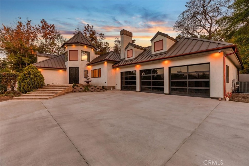 The pièce de résistance of Orange Park Acres glows in the California sun and welcomes you home! This gorgeous gated 3,381sqft architectural masterpiece nestled amongst the countryside exudes modern amenities, a triad of sophistication, elegance and functionality. As you approach this phenomenal estate, the custom welded 22ft gates with commercial grade mechanics sets the stage for a grand entrance with a high tech security system. The oversized driveway provides a generous parking area convenient for the arrival of your VIPs. The front elevation shows immaculate attention to detail with the aesthetic appeal of a modern castle with turret-style entry, 22 gauge Standing Seam metal roof girdled with copper gutters. A 3-coat smooth stucco finish with dual waterproofing layers over all new plywood creates formidable protection and elegance. Heavy-duty aluminum and glass garage doors have sleek lines and reflect a stately design. The backyard area is surrounded by full-grown trees, terraced/cleared grounds with stunning mountain views and hardscaping for a beautiful patio setup. Once you cross the threshold of the stately double door entry with Baldwin hardware, a warmth exudes from the neutral-toned sustainable European flooring and custom Anderson windows. A chef’s dream awaits in the well-designed kitchen with bountiful cabinets and waterfall island made with high end Taj Mahal Quartzite, floating display shelves, open cabinetry and a 60” Wolf Dual Fuel range and Sub Zero Pro 48” refrigerator. Two Fireclay Farmhouse kitchen sinks with Brizo Litze Gold faucets and pot-filler makes cooking and cleaning up, effortless. Relaxation is maximized as you escape into your Primary Suite with ensuite spa bathroom with a black stone-resin freestanding soaking tub as the centerpiece. A large glass rainshower with natural stone surround brings calm and serenity to your retreat. The comfort continues with all Kohler Smart toilets with bidet and remote/manual flushing options. An upgraded Navien instant water heater will keep your extraordinary tub warm for hours of soaking.This equestrian estate knows how to pamper your four-hooved friends with a rustically elegant restored barn re-roofed with architectural shingles and gutters, covered stable and turn out area. No horses in your world? This versatile space can be used for added storage, car collection, an amazing event venue for parties and gatherings, or a “he/she shed” getaway. OPA offers…Community…Trails…Privacy, ETC!