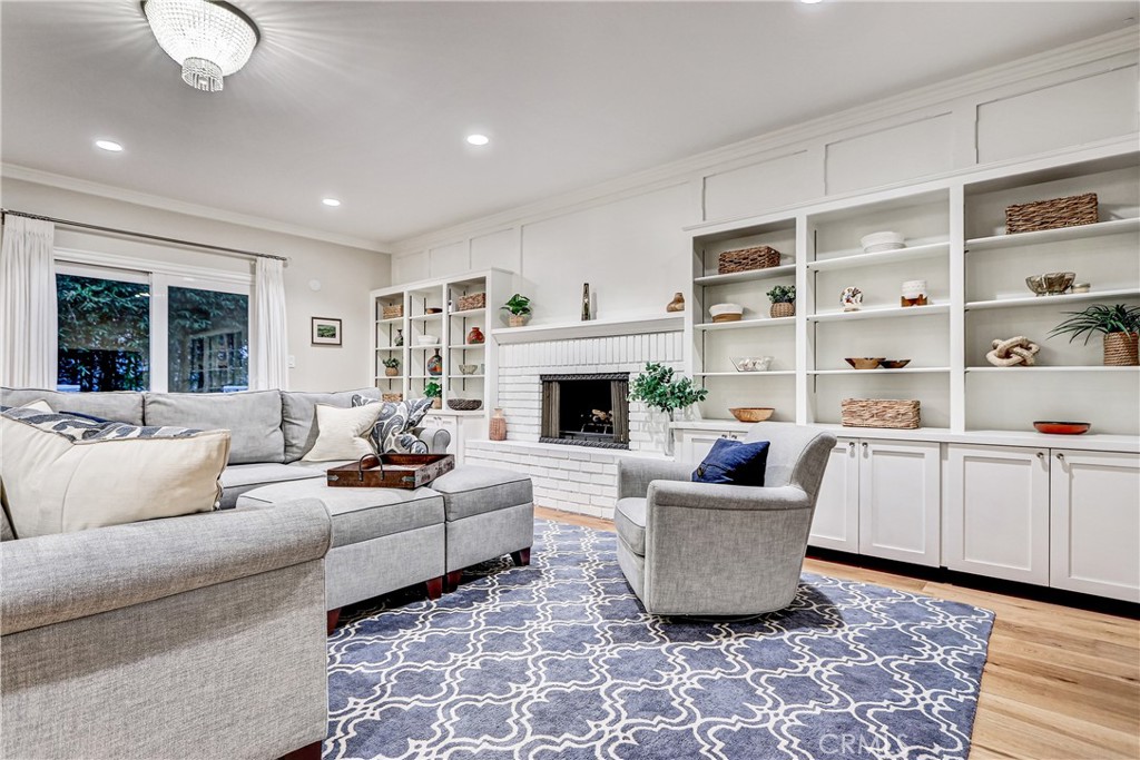 Perched on a high vantage point with a city and mountain view, this luxury residence offers a rare blend of architectural integrity, thoughtful updates, and that elusive sense of place that design-savvy buyers recognize the moment they walk in. From the Cape Cod–inspired exterior to the artful vintage details inside—refinished brick fireplaces, warm wood-beamed ceilings, and Deco-inspired finishes—this home appeals to anyone with a keen eye for authentic California design. These are not trendy add-ons; they are rooted elements of classic LA architecture, sparking inspiration for personal expression with very little effort. The floorplan is equally intuitive: all bedrooms are thoughtfully placed upstairs, creating a private retreat from the entertaining spaces. The main level flows easily from formal dining to casual family hangouts, with multiple living spaces, including a large den, and a family room that is open to the kitchen, and a sunny, indoor-outdoor connection to the backyard. Additional highlights include a large, tranquil office with vaulted ceiling, en-suite bathroom and a front-facing balcony, a two-story white-brick fireplace, custom-built-ins, wide-plank hardwood floors throughout, dual-zone Nest HVAC, a sound system compatible with Sonos, a proper laundry room, and an oversized three-car garage. Throughout the home, custom storage and organized closets reflect thoughtful planning. The spacious primary suite is a retreat in itself, featuring vaulted ceiling, two closets, a spa-like bath with jacuzzi tub, radiant heated floors, vessel sinks, full linen storage, built-in toiletry pockets in the shower, and dimmable designer lighting to set the tone. Downstairs, the family room flows directly to the sunny, landscaped backyard. The deck is the perfect spot to enjoy near-perfect SoCal weather, dining outside, casually lounging around a fire-feature and enjoying yard games. The backyard also features bamboo privacy plantings, and a grassy lawn—your own private space to listen to summer concerts in the park, located just a block away! Conveniently situated in a beloved neighborhood with close proximity to award-winning schools, one block from sports fields and public pickleball and tennis courts. Trader Joes, Target, and main commuter routes are close by.