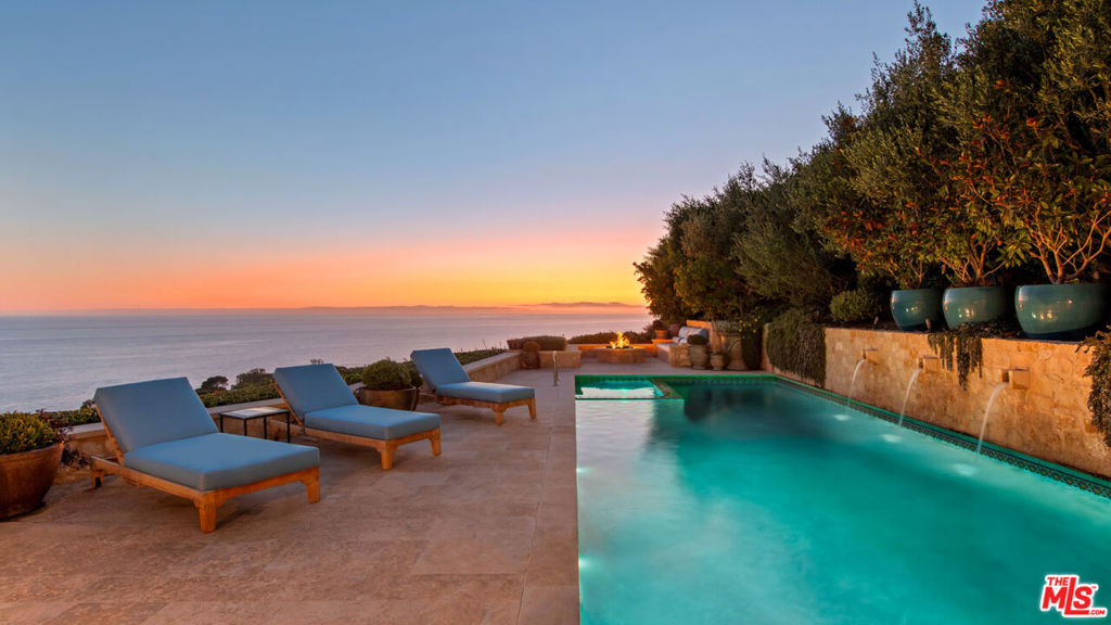 Experience unparalleled luxury in this exquisite French Country-style estate, a masterpiece of European design by renowned builder Paul Brant Williger. Nestled in a coveted location, this architectural gem offers breathtaking ocean views, world-class amenities, and meticulous craftsmanship. A stone-arched entryway welcomes you into a home where high ceilings, reclaimed French oak floors, and antique wood beams exude sophistication. The living room boasts a vaulted ceiling, an antique wood-burning fireplace from France, and seamless indoor-outdoor flow. The adjacent great room features a firewood nook, perfect for cozy evenings. The chef's kitchen is a culinary dream, featuring a massive quartzite island, Caesar stone counters, and top-tier appliances, including a 6-burner Wolf range, dual Miele dishwashers, Sub-Zero refrigeration, a built-in Wolf microwave, and a Miele coffee machine. Custom antique French tiles, vaulted ceilings, and a built-in bar with wine storage enhance its charm. The formal dining room showcases a fireplace, vaulted wood-beamed ceilings, and stunning coastline views. Nearby, a powder room impresses with French tile floors, a floating sink imported from France, and custom lighting. The primary suite offers ocean and pool views, a fireplace, and sliding doors to the backyard. Its spa-like ensuite features a mosaic tile floor, stone counters, a double vanity, a walk-in shower, a marble bench, and an in-ground soaking tub framed by French windows. Additional bedrooms provide vaulted ceilings, walk-in closets, and elegant baths with imported tiles and custom finishes. A converted garage serves as an office or gym with built-ins, skylights, and French doors opening to the garden. A well-appointed laundry room adds convenience with built-ins, a new washer and dryer, and a wine fridge. The backyard is a private oasis with panoramic ocean views, a rectangular pool with a built-in hot tub, a fire pit with a custom-built couch, and a tranquil waterfall feature. A covered dining area, complete with infrared heaters and an exterior fireplace, ensures year-round entertaining. Hand-finished French limestone throughout the yard provides a slip-resistant surface. This home's construction showcases unparalleled craftsmanship, from imported antique doors to a handmade Tuscan tile roof. Modern amenities include ultra-sound-resistant glass windows and sliders, push-button automatic shades, a whole-home generator, three-zone climate control, and a full security system. With four fireplaces, four fountains, and breathtaking sunsets over Little Dume, this estate offers an unmatched living experience.Featured in Luxe Magazine and two HBO productions, this residence is part of an upcoming gated, fire-wise community with low HOA dues. Every detail, from antique French tiles to Excalibur hand-finished plaster walls, reflects a timeless European retreatelegant, refined, and truly extraordinary.