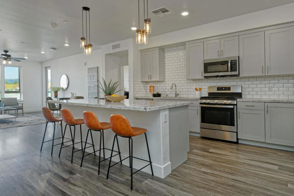 SINGLE-STORY! One of the most desirable floor plans at the Prestigious Avenue One Community! Bathed in Natural Light. Still feels brand new! Full width-of-unit balcony with views of hills. **2 assigned parking spots in secure underground garage, also an EV Charging Station.** Stunning kitchen has Large Island with eating space and beautiful Quartz Counters. Bright, open & spacious. Custom cabinets, SS Appliances, Gas Stove, Convection Microwave. Refrigerator, washer and dryer included. "Extra" convenient room used as Den or Office/Study. Luxury Vinyl Tile throughout main areas and bathrooms, cozy carpet in bedrooms. Light & bright bedrooms have large walk-in closets; Primary bath has dual vanity and spa-size step-in Rain Shower. Tech savvy CAT6 wiring and Fiber Ready. Secure building access, Elevator. Very easy access to the Resort-style 12,000 sq ft Clubhouse which offers lovely lounges, fireplaces, meeting areas, Gym, Yoga & Exercise Rooms, Giant Pool & Spa, a Commercial Kitchen/Event Center that can be rented for private events. Community BBQ/Picnic Areas, playgrounds and community gardens are close as well as gated Dog Park and multiple parks/playgrounds. Shopping Center and Dining nearby. Close proximity to 87/85/101, also VTA Light Rail and Cal Train.