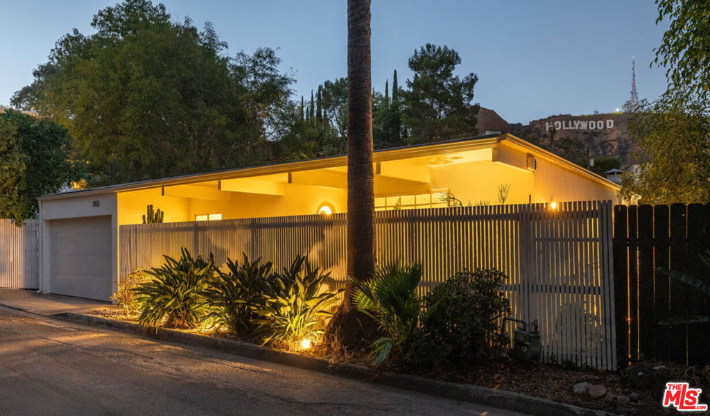 THE QUINTESSENTIAL L. A. MID-CENTURY ON COVETED DURAND DRIVE. This pristine, move-in-ready architectural diamond offers a fantastic open floor plan with floor-to-ceiling windows that fill the interiors with natural light, seamlessly blending the indoors with the outdoors. Hardwood floors extend throughout. The private courtyard entry opens to a foyer that draws the eye straight through the house to the spacious living room and nature beyond, is complete with a fireplace. A secondary seating venue with built-in bookcases provides direct access to a gorgeous balcony perfect setting to relax and take in the surrounding canyon views. A fully equipped kitchen with a breakfast bar flows into the dining area. The primary bedroom is located on the main floor, along with two full bathrooms. Downstairs, you'll find another bedroom and a large flex room that can be used as a bedroom, studio, office, or creative space. Every room in the home enjoys sweeping views of the iconic Hollywood Sign. An attached, direct-access one-car garage adds convenience, while authentic mid-century details are showcased throughout.