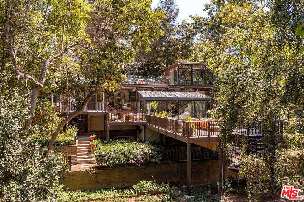 Beyond a gated entrance in Rustic Canyon, this exceptional and unique property unfolds across nearly an acre of land, with organically landscaped grounds, offering a rare blend of architectural distinction and natural beauty. The main residence (5 bedrooms/5 baths) is a bold and timeless architectural statement, with soaring lines and walls of glass that invite in light and frame tranquil vistas. A separate guest house (2 bedrooms/2 baths) provides luxurious accommodations for guests, an office or private creative space. A picturesque creek winds through the property creating a meditative backdrop for daily living. Expansive terraces and garden pathways invite gatherings and natural settings for reflection. Designed for those who value balance, this estate embodies a retreat-like atmosphere - equally suited for spiritual renewal and entertaining. This is a rare opportunity to own an exclusive compound where architecture, lifestyle and nature exist in perfect harmony. A must see!