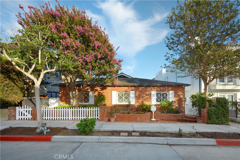 Set on a coveted 40-foot wide lot along Corona del Mar’s prized 200 block, this single-level residence embodies the charm and sophistication of village living. Offering approximately 2,468 square feet with 3 bedrooms, 2 bathrooms, and the rare convenience of a two-car garage below, it enjoys a location just moments from Little Corona beach, boutique shops, and local dining.
A Dutch door entry reveals light-filled interiors where vaulted, beamed ceilings, crown molding, and a welcoming fireplace framed by custom built-ins create warmth and character. French doors open the living room to a balcony with treetop vistas and ocean breezes, while the kitchen—appointed with Calacatta Prado countertops and crisp cabinetry—flows easily into the dining area and outward to a private front patio.
All three bedrooms are located on the main level, with the primary suite offering vaulted ceilings, generous storage, and a redesigned bath that blends elegance with ease. Fresh paint, new flooring, and remodeled baths further refine the home, striking a balance between timeless charm and modern updates.
Wide frontage, classic details, and a sought-after setting in the heart of Corona del Mar make this residence a rare offering where coastal lifestyle and enduring style meet.