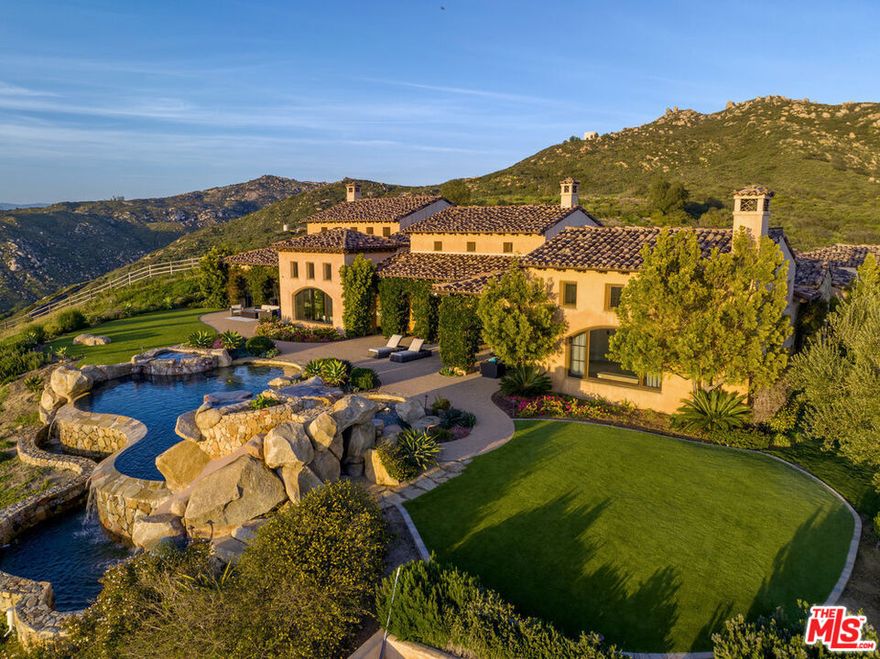 Nestled atop the mountains, this stunning Mediterranean villa boasts breathtaking 360-degree views and sits on approximately 5 acres of land within the exclusive gated community of The Heights. As you enter, you'll be greeted by soaring ceilings and doorways that create an airy, light-filled ambiance. The chef's kitchen is a culinary masterpiece, featuring sleek stainless-steel appliances, new marble countertops, and an inviting seating area. The family room is the epitome of open concept living, seamlessly connecting to the alfresco dining area with a built-in BBQ, pizza oven, and ample seating. One wing of the home offers a game room, movie theater, two ensuite bedrooms, a mudroom, and an oversized 4-car garage with plenty of storage. The spacious primary retreat is a true oasis, complete with a cozy fireplace, a sprawling bathroom with a jacuzzi tub and an oversized stone shower, new marble countertop vanities, and two water closets. The other wing of the home features two ensuite bedrooms, a laundry room, and an executive office with exquisite, chauffeured wood ceilings and paneling. The backyard is a dream come true, with an infinity-edge pool and spa with waterfalls, full tennis court and fenced in children's playground. This property offers complete serenity and privacy - a rare gem that must be seen to be appreciated.