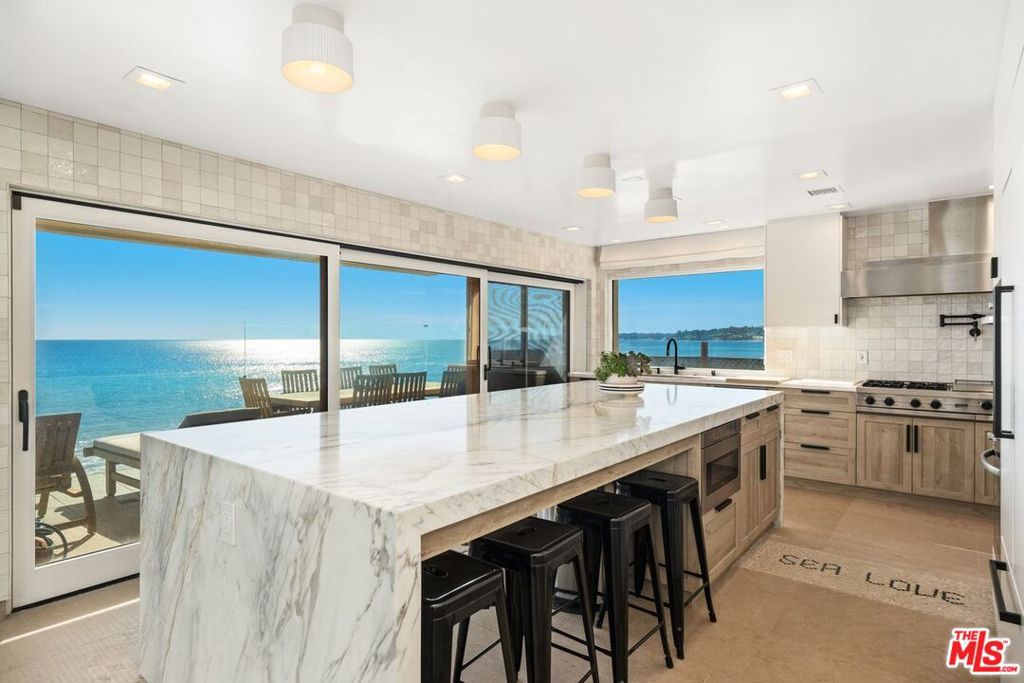 Fully furnished and ready for move-in immediately!! This property spans 50ft on the deepest section of beach on Malibu Rd & has unobstructed panoramic ocean views of Santa Monica Bay, Catalina & Point Dume. The property features a dual gated entry, driveway w/ ample secure parking & courtyard that leads to the custom fossilized front door. The main floor is expansive & features an open floor plan w/ formal dining area, living area w/ double-height ceiling & newly remodeled kitchen w/ a massive marble island, custom cabinetry & brand-new stainless-steel appliances by Viking and Wolf. An abundance of natural light fills the space w/ a large skylight & floor-to-ceiling sliding glass doors that open to a large balcony w/ glass railings that span the width of the house. The primary suite encompasses the entire top floor w/ his & her walk-in closets, custom blue marble bathroom w/ dual vanity & water closets, skylight & soaking tub w/ ocean views. The primary bedroom features a fireplace & sliding glass doors that lead out to the balcony & west facing sunset views. The bottom floor features three additional en-suite bedrooms, one of which is oceanfront w/ direct balcony access & the other has triple bunkbeds. Lastly, there is an oceanfront den, laundry room & private beach access. Centrally located off PCH in the highly desirable Malibu Rd community w/ easy access to world class dining at Nobu or Lucky's, designer shops in the Country Mart & countless miles of hiking at Bluff's Park & Puerco Canyon.