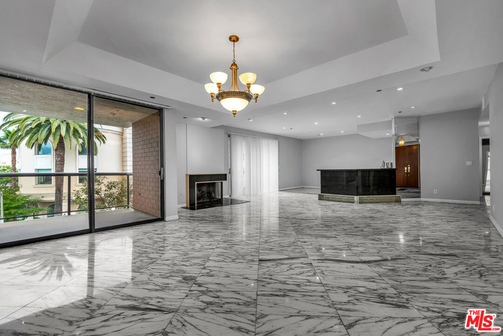 SPECTACTULARLY SPACIOUS condo w high ceilings and TONS of light! Enjoy one of the largest (2,003 sq ft) open, layouts in Beverly Hills. Stunning marble design flooring throughout. Expansive layout offers central fireplace, large balcony and space for your largest furnishings from living room suites to statement dining room tables. Wet bar separates the living area and your open den. Gourmet Kitchen has stainless steel appliances, ample storage and an extended dining area. Primary bedroom has an abundance of space and walk-in closets. An ensuite spa bathroom offers a sunken jet tub and separate shower. Lovely 2nd bedroom is totally separate w its own large space, sliding door closet and ensuite bath/shower feature. Enjoy a secure, private building entry and two side by side parking spaces. All just minutes away from Beverly Hills, Restaurant Row and Sunset Strip. Ready now!