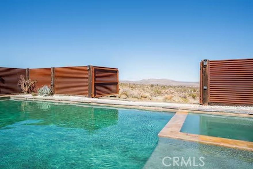 Escape to this gorgeous pool home on a generous 5 acre lot in one of Joshua Tree's most desirable neighborhoods! Less than 3 miles from the National Park entrance, the location can't be beat. At almost 2600 square feet this spacious home enjoys sweeping views of the valley, high ceilings, and a touch of southwestern flair. Enter the home through the antique wooden door brought up from Mexico and you're greeted by custom wooden barn doors on either side of you leading to bonus rooms (originally den and dining rooms) now being used as additional bedrooms. Continue into the great room where you find a cozy family room complete with a pellet stove and reclaimed wood mantle. To your left is the dining area, and behind you the open kitchen. The kitchen features granite countertops, built in appliances, and tons of storage. Stand over your copper sink at the kitchen island and past your loved ones and onto the panoramic desert view through your sliding doors. On one side of the home you'll find a half bathroom as well as a primary bedroom en suite w/ a sliding door for more views, and a gorgeous en suite bathroom featuring a jetted spa tub, double vanity, walk-in shower, and walk-in closet. This entire suite is filled with natural light during the day and a peaceful distance from the other bedrooms at night. The other side of the home features two more bedrooms each with their own in-room vanity and a jack 'n' Jill bathroom. There is a laundry room that includes two sets of washer/dryers, cabinets, and a utility closet. The home features Central heat and air conditioning (2 units), central vacuum, ceiling fans in all rooms, and Nest thermostats. 



Now for the real showstopper, the outdoors! The covered back patio looks down onto your fenced and heated in-ground sparkling pool and spa. Large swinging back gates allow you to open them for a panoramic desert view from inside of the pool area as well, or turn off the interior pool/spa lights and gaze up into the starlit night sky. Off the front patio you'll find tons of parking, a large 3 car garage (currently a game room) with a built in counter and mini-fridge, and 2 OWNED extra-large propane tanks which allows you to negotiate on your propane costs. This lot also features plenty of land where previous owners enjoyed keeping horses. From copper sinks to railroad tie fence posts, this home has a truly special feel. Continue it's run as a highly successful Airbnb  or make Cope Compound your very own paradise!