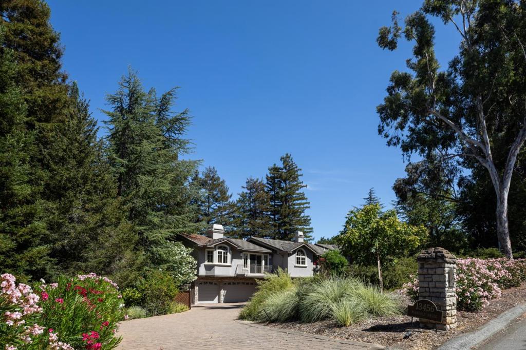 This beautifully appointed resort-like home, with 6 bedrooms, office, and 6.5 baths, is positioned on one acre of private grounds. Tiled and maple floors enhance the spacious interiors, which begin with a dramatic living and dining room with soaring wall of glass rising to the cathedral ceiling, a library area, and fireplace. The gourmet kitchen with granite counters and high-end appliances opens to the family room with a fireplace and numerous sliding glass doors open to rear balconies with stairs down to the pool. The main level comprises the primary suite with fireplace, an additional suite, two bedrooms that share a bath, plus a bedroom and bath privately located near the family room. The lower level offers a bedroom suite, customized office, recreation room with refreshment bar, and fitness center, each with outside access. There is a sunswept pool and spa, tucked away large fenced sport court, beautiful redwood groves, and a sunny side yard with vegetable beds. Top Palo Alto schools complete this exceptional solar-powered home.