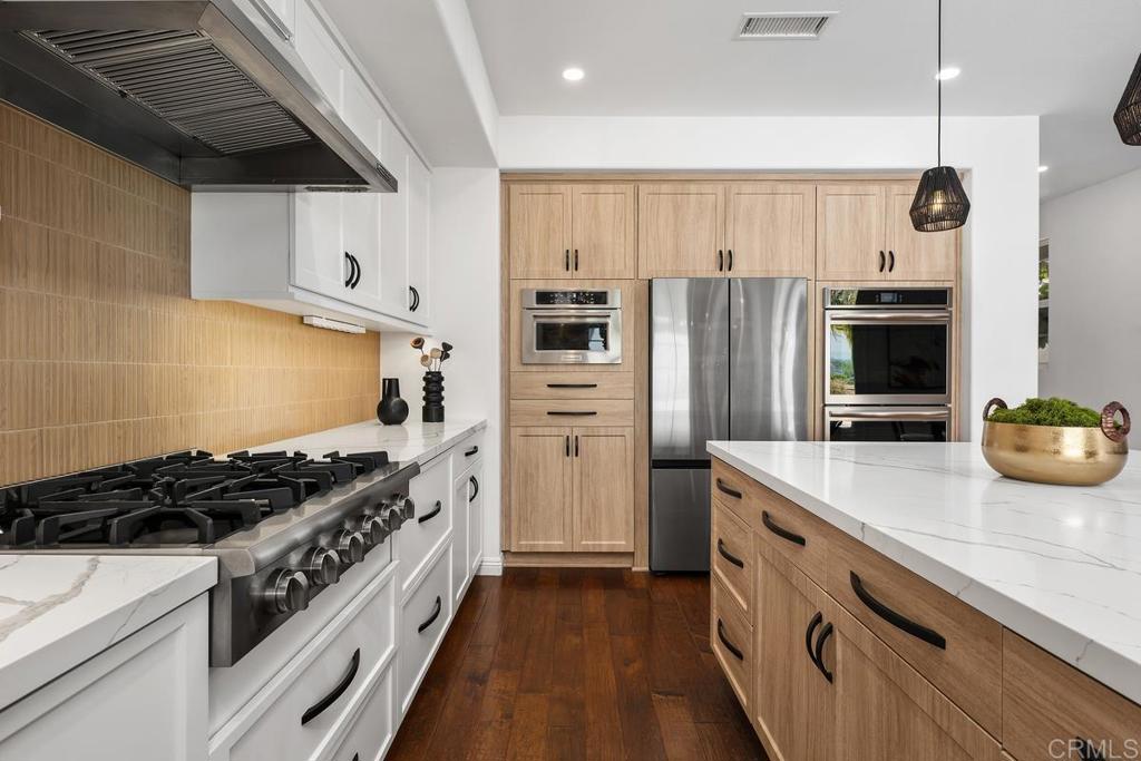 Tucked away in the coveted La Costa Oaks South community, 7661 Sitio Algodon is a meticulously cared-for residence offering panoramic westerly views, a flexible floorplan tailored for today’s lifestyle, and a tranquil cul-de-sac setting. The recently renovated kitchen is a chef’s dream, showcasing a generous island, modern finishes, a brand-new 2025 Thor cooktop, Bosch dishwasher, Frigidaire double oven, and KitchenAid microwave. Freshly painted throughout, the main home features four upstairs bedrooms and two-and-a-half baths, plus a fully self-contained ground-level studio ADU—complete with its own private entrance, bathroom, kitchenette, and outdoor patio, ideal for guests, multigenerational living, or added income. Upstairs, the luxurious primary suite feels like a private retreat, boasting a remodeled spa-style bathroom, including Mr. Steam steam shower with chroma light, and a custom oversized deck with a hot tub—the perfect place to unwind and take in sunset views. Designed for effortless indoor-outdoor living, the home offers spacious interiors, a beautifully appointed courtyard with fireplace, a low-maintenance backyard with a fire pit, built-in BBQ, covered pergola, and wide-open ocean views. Additional highlights include owned solar, a car charger, and a whole-house water filtration system. Enjoy access to award-winning schools, resort-style community amenities, scenic trails, shopping, and beaches—all in one of North County’s most desirable neighborhoods.