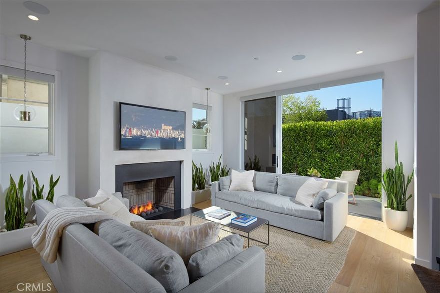 Embrace coastal living at its finest with this sun-drenched, contemporary front-unit residence in the heart of Corona Del Mar. Boasting a thoughtfully designed open layout, the property seamlessly integrates expansive living areas. At the center of this design is the great room, where glass pocket sliding doors create a fluid transition between the indoor living spaces and the charming outdoor environments. An en-suite bedroom, a living room warmed by a cozy fireplace, a dining space, and a chef's kitchen complete the first level. Here, professional-grade appliances meet an oversized island and designer pendant lights, highlighting a breakfast bar perfect for morning gatherings. Accommodating four elegant en-suite bedrooms, the expansive primary suite features vaulted ceilings, a luxurious bathroom, a walk-in closet, and a private balcony for serene moments. Outdoor areas include a welcoming front porch, a side patio with its own fireplace, the balcony off the primary suite, and a spacious rooftop deck. Equipped with a refrigerator and ice maker, the rooftop offers sweeping views of city lights and the gentle sea breeze with minimal obstructions. Superb craftsmanship and meticulous attention to detail exemplify this sleek yet inviting abode. Additional luxuries encompass an office/bonus room, an attached single-car garage, and a prime location close to the bustling shops, pristine beaches, and exquisite dining options of Corona Del Mar. Modern conveniences include a full AV system, automatic window coverings in the living areas, TVs on all decks, and elegant quartz and stone countertops throughout.