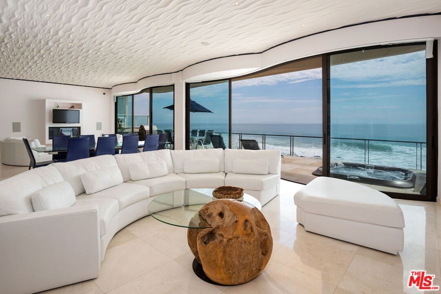 Dolphin House with celebrity style, and 55 feet of Malibu Road beach frontage, Sinuous curves, white marble floors, and sleek contemporary furnishings. Walls of glass and two spacious beachfront balconies take in the expansive ocean and island panorama. The main living area is wide, curved Fleetwood stacking glass doors open onto a full-width deck complete with Jacuzzi, Lynx barbecue. The living area comprises two seating areas with exquisite Italian leather furniture, two flat screens, and a fireplace (one of four in the home). Between the sitting areas is a stunning glass dining table for ten guests, and adjacent to that is a fully equipped and stocked horseshoe-shaped bar with a beverage cooler, custom chandelier, and bar seating. The dual-island gourmet kitchen features wood cabinets, rare granite, and onyx countertops, top-of-the-line appliances, an indoor grill, a dumbwaiter to the second-floor kitchenette. Upstairs, accessible by steps or elevator, are three suites, two with ocean views and curved glass doors onto another full-width deck, and one suitable as an office, media room, or guest suite. Lavish spa-style bathrooms, equipped with integrated smart-home amenities, air conditioning, radiant floor heating, security, a two-car garage, standby generator, intercom, and automated sun shades. Lease price to be $45,000 for 1 year term leases. Summer 2026 rate to be.. June $50,000, July and August $69,000 per month, September $50,000 per month. Short term rate to be $47,000 per month