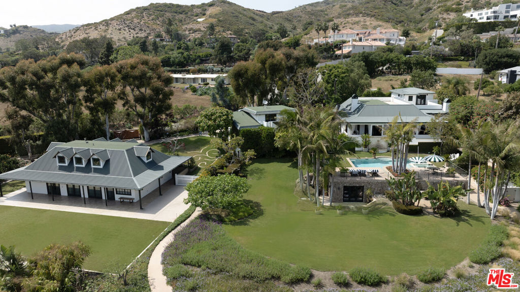 Seaside Sanctuary! Discover an unparalleled coastal retreat at Seaside Sanctuary, a breathtaking ocean-view compound in Malibu. Set on 1.6 lushly landscaped acres, this private estate features two separate residences, offering luxury and serenity.The main residence boasts five spacious bedrooms, each with ensuite bathrooms and private patios that connect to scenic pathways around the lush gardens. A unique wrap-around veranda adds charm and invites you to enjoy the tranquil surroundings. The second residence features three bedrooms, three baths, and wrap-around covered seating areas, making it an idyllic haven for guests or family. Exceptional property highlights include: Detached gym and studio for your lifestyle needs. Two EV fast chargers in the garages for modern convenience. Three-car garage and three gated entrances, including a service entrance. Sparkling pool and spa, complemented by lush grass and an elegant outdoor fireplace with stone enclosure. Backup generator and well water system to ensure security and sustainability. Two laundry rooms, one in each residence, for ultimate practicality. Night landscape lighting, creating a magical evening ambiance. Located in mid-Malibu, this tropical estate provides easy access to beaches, schools, and shopping while ensuring unparalleled privacy. Make this extraordinary Malibu compound yours and immerse yourself in coastal luxury.