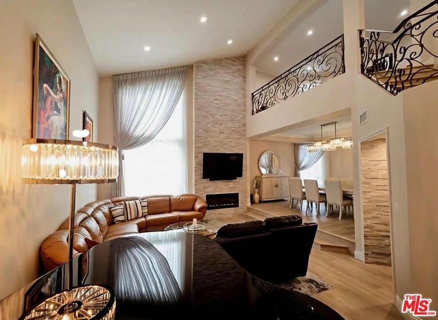 Welcome to this extraordinary penthouse residence where meticulous craftsmanship meets contemporary elegance. Spanning 2,100 square feet of thoughtfully reimagined space, this completely remodeled condo represents the pinnacle of Encino living. Upon entry, you're immediately captivated by the soaring cathedral ceilings in the living room, creating an impressive sense of volume and openness. The great room showcases designer lighting fixtures, including a stunning crystal chandelier, and features a floor-to-ceiling stone accent wall housing a sleek linear fireplace. Elegant drapery frames floor-to-ceiling windows that flood the space with natural light. The home's crown jewel is the expansive primary suite, a true sanctuary offering generous proportions and direct access to your private walk-in closet featuring custom built-in shelving with warm wood backing for a high-end boutique feel. The spa-inspired primary bathroom is nothing short of spectacular, with its modern gray palette, marble-look porcelain tile, freestanding soaking tub, frameless glass shower enclosure, and dual vanities with quartz countertops. The kitchen balances style and functionality with white shaker cabinetry, stainless steel appliances including double ovens, granite countertops, and abundant storage including glass-front display cabinets. A secondary bedroom offers serene tones and classic furnishings, while an additional contemporary bathroom features backlit mirrors and clean lines. Step outside to your private rooftop deck  an entertainer's dream with wood-look porcelain tile accent walls providing both privacy and modern aesthetic appeal. This expansive outdoor retreat offers the perfect setting for al fresco dining and relaxation under the Southern California sky. Practical luxuries include a dedicated laundry room and convenient side-by-side parking. The prestigious community offers resort-style amenities: two sparkling pools, two spas, sauna, recreation room with pool table, and secure gated entry with controlled access. This penthouse is available unfurnished or as a rare turnkey opportunity  fully furnished with designer pieces, complete cookware, dining ware, electronics, and artwork as photographed. Simply bring your suitcase and begin living the elevated lifestyle you deserve. Experience penthouse living where every detail has been carefully curated for the discerning resident seeking both luxury and convenience in one of the Valley's most desirable locations.