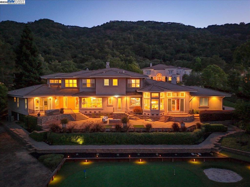 Sweeping views and exceptional privacy define this custom estate at the end of a quiet cul-de-sac in Pleasanton’s prestigious guard-gated Golden Eagle community. Set on nearly an acre and backing to permanent open space, the property offers unobstructed vistas of Mt. Diablo, Pleasanton Ridge, and the scenic valley. The main level features a luxurious primary suite with backyard access, a private home office, and a guest suite—ideal for multigenerational living or guests. The chef’s kitchen boasts cherry cabinetry, granite countertops, and high-end stainless appliances, opening to a dramatic family room with walls of windows and abundant natural light. Formal living and dining rooms offer elegant entertaining spaces, enhanced by custom finishes and a built-in wine closet. Upstairs includes two spacious en-suite bedrooms and a large bonus room with full bath—perfect as a fifth bedroom, media room, or playroom. A 4-car garage provides generous storage and flexibility. Outdoors, enjoy stone patios shaded by mature oaks, a private putting green, and serene surroundings—all just minutes from downtown Pleasanton, top-rated schools, and commuter routes.