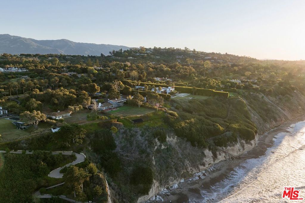 Envision your best coastal California life, cultivated from the legacy of this rare, 2.5+ acre bluff front estate. Gracing the Hope Ranch coastline and boasting world-class ocean views, this enchanting property offers exceptional privacy, ample space & amenities, and nearly endless opportunity.Past the front gate, the private driveway meanders through verdant avocado and lemon orchards, opening to breathtaking views as you approach the motor court and main residence. Surrounded by abundant flat, usable acreage and a symphony of lush landscaping, the expansive home and property provide a ready canvas for a true oceanside compound: a 5,200+ square foot main residence with stunning views from nearly every room, a private guest suite, an attached 3-car garage, a spacious patio & pool area, and the potential to incorporate additional structures into this beautiful estate.The two-story home features an inviting central living area with vaulted open-beam ceilings, an enormous fireplace, and massive picture windows framing the timeless vistas. Additional main floor rooms include an office/den, dining area, kitchen & breakfast nook, and 3 guest bedrooms. Upstairs, the secluded and spacious primary suite makes use of the entire upper level, capturing elevated views of the sprawling grassy lawn and the ocean beyond. The attached 1 bed/2 bath guest suite features a full kitchen, a spacious living area, and its own separate entrance.The world may be your oyster, but this special property invites you to discover the treasure of a home that cannot be replicated -- an everyday getaway where you and those you love can rest, relax, & recharge. From the tranquility of your own oceanside botanical oasis, wake up daily to the fresh salt-air breeze, ever-inspiring ocean-&-island panoramas, and the soothing sounds of the waves below. The entire property is a gardener's paradise, filled with various fruit orchards, breezy palms & shady oak trees, Birds of Paradise & other flowering plants -- even a greenhouse in which to tend more delicate flora.Located on a rarely available street, this legacy parcel embodies the elegant but understated way of life that defines this coastal community. Hope Ranch residents can enjoy private beach access, bridle & equestrian trails, dedicated security patrol, community tennis courts, and convenient proximity to the La Cumbre Country Club & Golf Course.