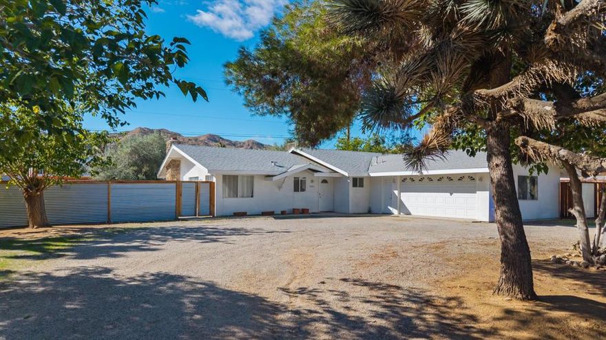 Located in Yucca Valley's picturesque Storey Park neighborhood, this 3-bedroom, 2-bath home sits on a near half-acre and offers an updated interior and a bright, open layout. Enjoy an inviting modern kitchen with sleek quartz countertops, stainless steel appliances, and abundant cabinet space. The dining area flows seamlessly into the living room, which is adorned with a large, beautiful stone fireplace and sliding doors that open to a covered patio. The spacious primary bedroom has generous closet space and an en-suite bath. Both guest rooms are well-sized and share the updated guest bath. The 2-car garage, currently utilized as a game room, offers laundry tucked conveniently inside. Out back, you'll enjoy the fully fenced yard, complete with tree-house, swings, fire pit, beautiful mature trees (including Olive and Joshua Trees) and a 15' vehicle gate has plenty of room to add amenities as you see fit. Just minutes from local shopping, dining, and Joshua Tree National Park