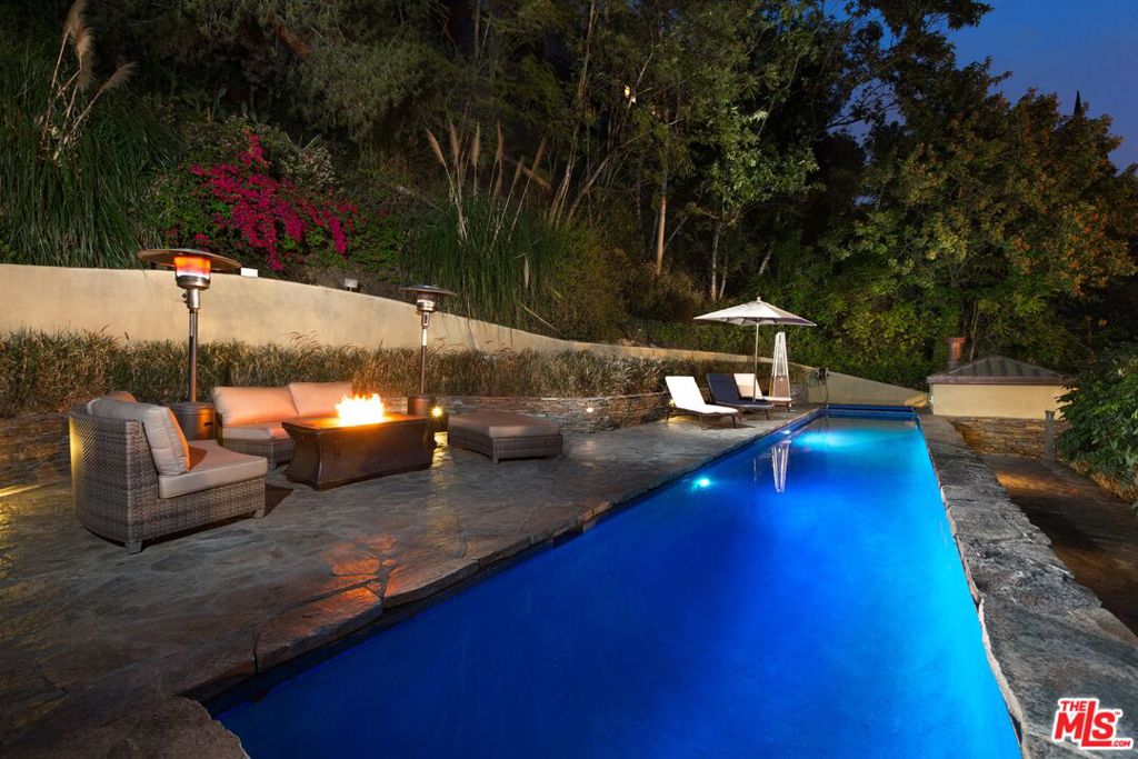 Tucked away in the prestigious hills of Beverly Hills, this private hillside retreat embodies refined luxury and timeless sophistication. Surrounded by lush greenery in the coveted Benedict Canyon area, this elegant estate offers a serene escape just minutes from world-class shopping, dining, and entertainment.Step inside to discover grand living spaces filled with natural light, highlighted by a stately limestone fireplace, a formal dining room perfect for entertaining, and a full-service bar. The gourmet kitchen is a chef's dreamequipped with top-tier appliances and designer finishes. Glide between levels in the striking golden elevator, adding a touch of glamour to everyday living.The primary suite is a sanctuary of comfort, featuring a cozy fireplace, expansive walk-in closet, and a spa-inspired bathroom with luxurious finishes. Outdoor living is equally exceptional relax by the heated pool surrounded by mature landscaping and manicured gardens, creating the perfect backdrop for quiet mornings or evening gatherings.This home is also outfitted with a premium surround sound system throughout, ensuring the ambiance matches your every mood. Ideal for high-profile buyers seeking privacy, tranquility, and elegance in one of L.A.'s most sought-after neighborhoods.