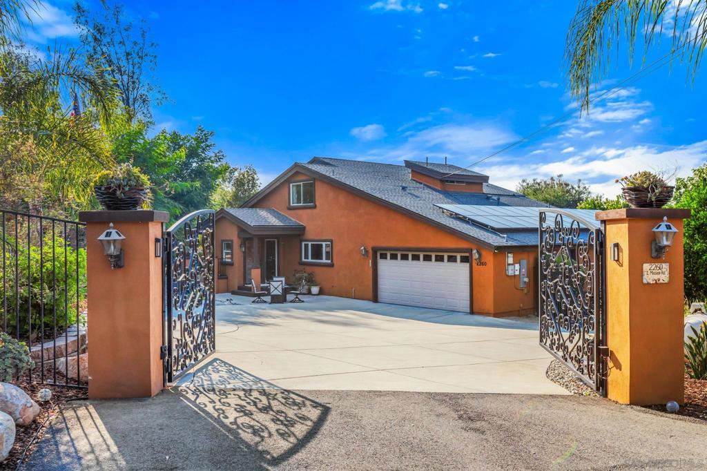 Pristine Fallbrook gated retreat on 1.64 acres, surrounded by lush landscaping and sweeping panoramic views. Beyond the double wrought-iron gates lies an exquisite custom home that seamlessly blends energy efficiency with extensive, tasteful renovations; crafted for both comfort and entertaining. The property is adorned with fruit and nut trees including pomegranate, citrus, loquat, kumquat, and macadamia, while a tranquil koi pond welcomes you at the entry. Inside, an open-concept design with vaulted ceilings, natural rock fireplace, warm wood accents, and expansive windows fills the home with light and gives it a cozy vibe. The chef’s kitchen shines with high-end appliances, pendant lighting, and durable composite countertops. The entry-level primary suite opens to a panoramic-view porch, and its spa-inspired bath features dual sinks, a soaking tub, walk-in shower, and rich wood cabinetry. Upstairs, a spacious loft overlooks the living room and offers flexibility as a third bedroom, game room, or secondary living space, alongside a generously sized second bedroom and full bath. Recent upgrades include a new roof, updated windows and insulation, a new heat/AC pump, and an owned 40-panel solar system. With breathtaking vistas of rolling hills, this private and peaceful oasis is truly a must-see!