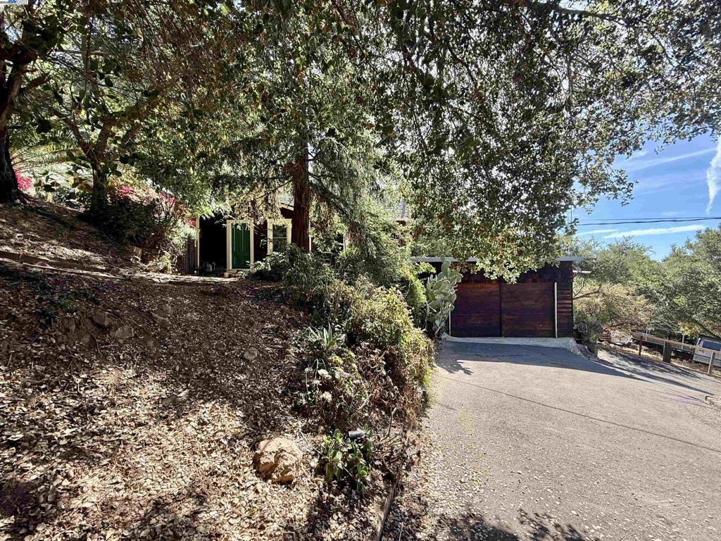 Tucked away in the sought-after Leona Heights neighborhood, this one-of-a-kind property is ready for your personal touch, whether you’re creating your dream retreat or crafting your next investment opportunity! Behind the gated entry and convenient drive-through driveway, you’ll find a private home with one bedroom and versatile bonus rooms, all set on an impressive 14,000 sq ft lot. Surrounded by nature and offering a peek at the bay, the single-level main living space charms with wood-paneled walls and floors, adding warmth and vintage character. Downstairs, a separate room awaits your imagination, perfect for a home office, workout zone, or creative studio. Multiple decks and tucked-away outdoor spaces invite you to relax, entertain, or soak in the peaceful setting. The large detached garage, separate laundry room, and abundant storage make daily living easy, while the oversized lot opens the door to expansion, custom landscaping, or potential future development. Enjoy the convenience of quick and easy freeway access- so close, yet you’d never know it’s there!