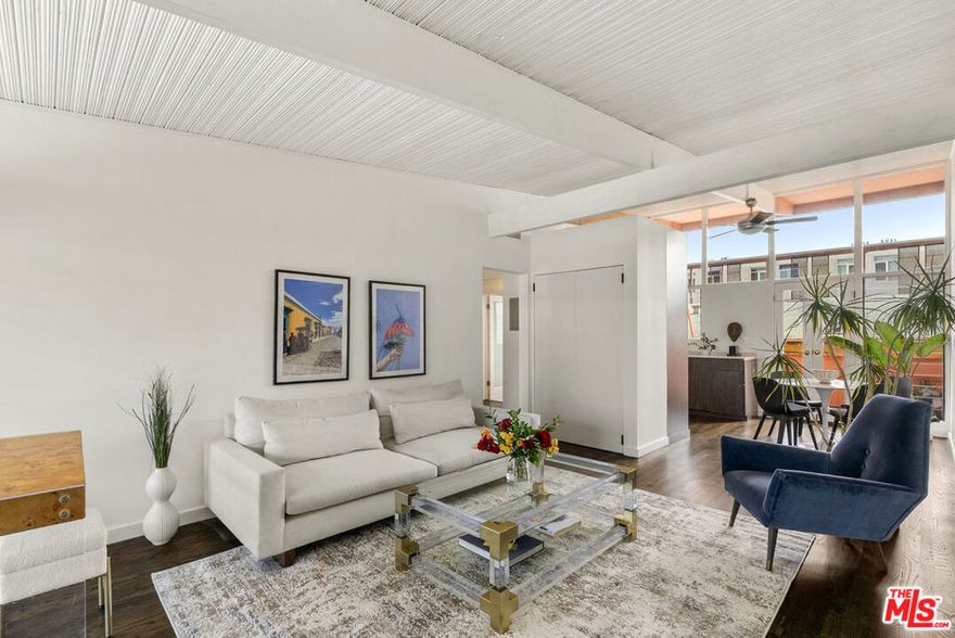 The iconic Hollywood Riviera is a celebrated West Hollywood landmark, designed in 1954 and embodying the quintessential mid-century Los Angeles aesthetic. Featured in publications such as Dwell and Architect Magazine, the building holds a coveted Mills Act historic designation, offering substantial property tax savings for its next owner. A recently completed renovation included earthquake retrofitting and a meticulous restoration of the common areas, returning the property to its original splendor. Residents now enjoy a resort-style pool with an expansive deck framed by lush tropical landscaping. This south-facing, upper-level residence showcases dramatic architectural elements, including vaulted ceilings, exposed beams, and floor-to-ceiling windows that bathe the interiors in natural light. Thoughtfully updated, the home blends authentic character with refined modern finishes. The kitchen is appointed with all-new custom cabinetry and appliances, Taj Mahal quartzite countertops, and clerestory windows. A renovated bathroom features a soaking tub, contemporary vanity, illuminated medicine cabinet, and upgraded plumbing.  Additional highlights include a newer HVAC system, generous in-unit storage, and a private balcony spanning the length of the residence. Secure, automated gated entry provides two covered parking space, a rare amenity in the neighborhood, along with additional garage storage. The building also offers on-site laundry, controlled access, and earthquake insurance.  Steeped in Hollywood history and often seen in film, television, and commercial productions, the Riviera remains one of West Hollywood's most enduring architectural treasures. Perfectly situated moments from the Sunset Strip's world-class dining, shopping, and nightlife, this residence offers the ultimate expression of California living.