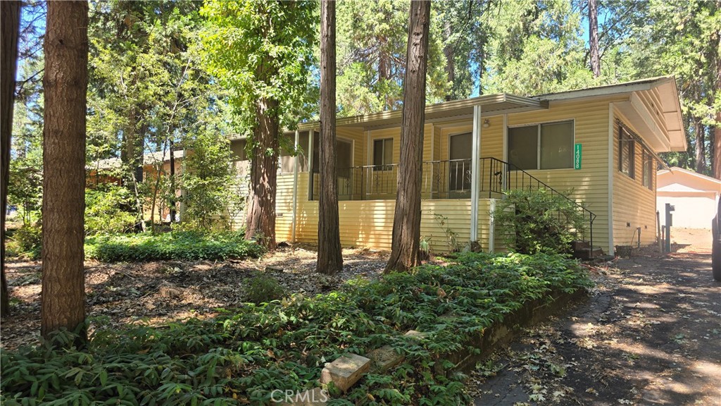 Located in a well-established neighborhood surrounded by mature trees and nearby homes, this property offers peaceful living in a beautiful part of Magalia. This manufactured home includes a detached garage and is just waiting for your personal updates and style. Step onto the covered front porch, which connects to a sunny bonus room — perfect for morning coffee, hobbies, or watching the sunset. Inside, you’ll find a spacious living and dining area with large picture windows that bring in plenty of natural light, plus a cozy wood stove to keep things warm during cooler months. The kitchen features a center island with a cooktop, ample cabinetry, and a small pantry for added storage. An indoor laundry room leads out to the covered back deck and backyard for convenience. New deck and awning just out the back door makes accessing your large backyard simple. The oversized primary bedroom includes a large full wall closet and a private bathroom with a walk-in shower and additional closet space. In the backyard, enjoy a quiet, shaded setting with a roomy storage shed and a detached garage for extra parking or workshop space. Both the front and back yards are low maintenance & level, with a paved driveway offering additional parking. This home also has new leach field for a fresh start on the septic system. The home itself is an estate sale and will need to be thoroughly cleaned and freshened up inside & out, but it seems to be good condition and just in need of some TLC!