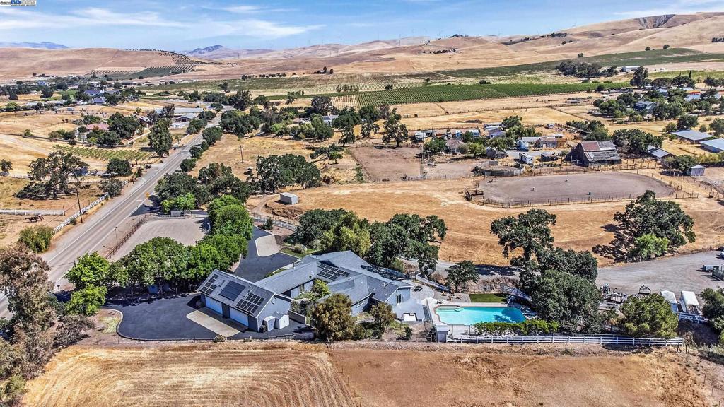OPEN HOUSE SUN 8/3 3-5 **Welcome to the Majestic Big Horn Ranch! This flat 5 acre ranch boasts a 3,400 sqft luxury home with a grand pool, sweeping patios, heritage oak trees, and a seasonal creek. The ranch also enjoys a 10-stall barn, lit riding arena, 40 x 60 shop, and a 2 acre pasture for grazing, roping, farming, ADU, or whatever you can imagine using a flat 2 acres for. At the heart of the home is a masterly designed granite and stainless steel kitchen with large center island and adjacent family room and dining room. No doubt the coveted gathering place for friends and family. Retiring to the primary suite is like escaping to your own private day spa retreat; large bedroom with fireplace, sitting area and views of the pasture, oaks and pool. The marble bathroom is host to a steam shower, large soaking tub, sitting area, wardrobe room and light streaming windows and skylights filling the room with the splendor of the outdoors. With four secondary bedrooms, four full bathrooms, office, four-car garage, 10,000 gal water storage, 30 gal-per minute well production, PV solar and a John Deere backup generator, all situated only 13 minutes from the flag pole in the center of town, the Big Horn Ranch is the quintessential Livermore Valley family compound.