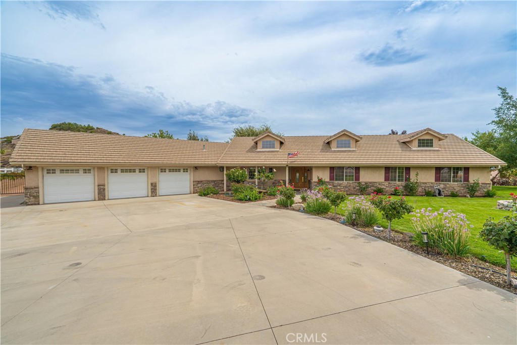 Stunning custom single-story gated estate on nearly 2 acres with breathtaking hillside views. This 4 bedroom 3 bath home features an expansive open concept floorplan with living area with oak hardwood floors, newer carpet, high ceilings, wood-burning fireplace, and whole-house fan. One bedroom with its own bath is privately located at the opposite end of the home, making it ideal for guests or multi-generational living. The spacious kitchen offers a granite island with breakfast bar, walk-in pantry, stainless steel appliances, recessed lighting, reverse osmosis system plumbed to the refrigerator, and abundant cabinet and counter space. The large master suite includes patio access, walk-in closet, and spa-style bath with decorative tile, glass shower enclosure, soaking tub, and bidet. Three bedrooms are located on one side of the home including a secondary suite with its own bath, ideal for guests or multi-generational living. Outdoor amenities include a covered patio, multiple seating areas, fruit trees, drought-tolerant Buffalo grass, and sweeping views of the surrounding hillsides. The 4-stall barn is fully equipped with water and electricity and the lower part of the property provides ample space for horses, corrals, storage, or a garden. Additional features include an attached extra-deep 3-car garage, abundant RV parking with 220V hookup, Hunter irrigation system for customizable watering, owned solar, public water, electric entry gate and paved road access. No HOA or Mello Roos. A rare opportunity to own a move-in ready ranch-style property combining privacy, functionality, and the perfect setting for entertaining or equestrian living.