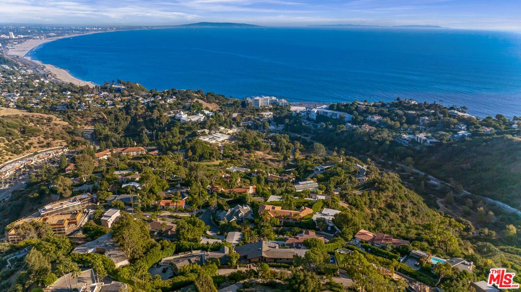 Breathtaking Pacific Palisades Mansion with Panoramic Ocean Views! Welcome to this magnificent 6-bedroom, 8.5-bathroom estate designed by the renowned architect Ray Kappe, offering unparalleled panoramic views from Downtown LA to Catalina Island, the Queen's Necklace, and the beaches of Malibu. Situated in the heart of Pacific Palisades, this stunning property is located moments from hiking and biking trails and all the best the neighborhood has to offer. Remodeled in the early 2000s, this home sits above the serene grounds of Lake Shrine, boasting the best views in the neighborhood. Floor-to-ceiling windows throughout capture the sweeping coastline, creating an incredible setting for both private relaxation and entertaining.The heart of the home features a fully equipped cook's kitchen with an open-concept design that flows seamlessly into the formal dining area, perfect for hosting. Additional highlights include multiple family rooms, a media/screening room, an exercise studio with an en suite bathroom, maid's quarters, and a custom wine cellar with a tasting area. Outdoors, enjoy the expansive deck overlooking the Pacific, with direct access to the lap pool and spa below a perfect backdrop for sunset gatherings or lounging in the sun. The two luxurious primary suites offer breathtaking ocean views, while the remaining three suites all include private en-suite bathrooms. This estate is equipped with an Enphase Solar Energy system for independent energy efficiency. The property includes a separate 3-car covered garage and a spacious 50' x 75' lower parking area capable of accommodating up to seven cars plus an RV, providing exceptional convenience. A charming guest house with a kitchenette and bathroom sits below the pool area, offering a peaceful retreat for guests. Experience luxury coastal living in this Zen-like atmosphere exceptional one-of-a-kind Pacific Palisades home, offering an unmatched blend of architectural elegance, modern amenities, and sweeping ocean views.