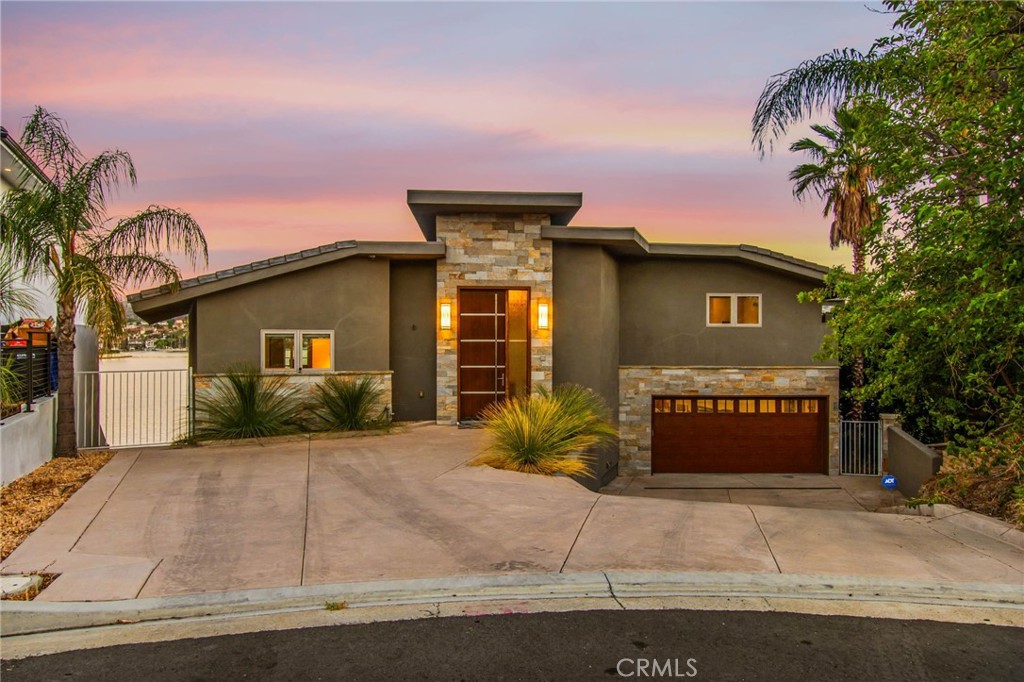 Experience contemporary waterfront living at its finest in this stunning 5,171 sq. ft. home, perfectly positioned on a premium ¼-acre main lake lot offering some of the most panoramic views in the entire community. From the moment you enter through the grand 10-foot solid mahogany door with stainless steel accents, you're welcomed by a dramatic foyer and a breathtaking wall of windows framing unobstructed views of the lake, beach, and surrounding hills. The main level offers an expansive open-concept design ideal for entertaining, with elegant lighting fixtures, chandeliers, blackout shades, and a built-in bar complete with a dumbwaiter to the lower level. Enjoy multiple flexible living areas for dining, relaxing, games, and media, all enhanced by a floor-to-ceiling stacked stone fireplace and a central theatre-quality whole-home audio and intercom system. The chef’s kitchen boasts custom hardwood cabinetry, quartz countertops, stainless steel appliances, and abundant storage. Two bedrooms and two full bathrooms complete the main level, along with a nearly full-width deck—perfect for taking in breathtaking SoCal sunrises and sunsets. The mid level hosts the luxurious primary suite with lake views directly from bed, oversized sliders opening to a private balcony, and a spa-like bath with dual vanities, soaking tub, walk-in shower with custom tile, and a spacious walk-in closet with built-ins. Two additional bedrooms with vaulted ceilings and walk-in closets offer more lake views, along with a full guest bath, a laundry room, and a versatile flex space currently used as an Escape Room. There is also direct access to an oversized 2+ car garage. Outdoor living is where this property truly shines, offering a lakeside putting green, pebble-tech pool and spa, a fully equipped outdoor kitchen with BBQ, sink, and concrete bar island, a private cabana, cozy firepit lounge, and a detached ¾ bath with an additional guest bedroom. Your private boat dock includes a hydrolift and fun waterslide—all tucked into a beautifully landscaped space designed for privacy and year-round enjoyment. This is lakefront luxury living at its best. Canyon Lake living offers a 400 acre waterski/fishing lake, 16 parks most with beaches and playsets, basketball, baseball, pickle ball, equestrian center, 18 hole golf course, pools, dog park, BMX pump track, golf cart friendly streets, slalom course, ski jump, restaurants, miles of hiking/biking/horse trails, community events and so much more!