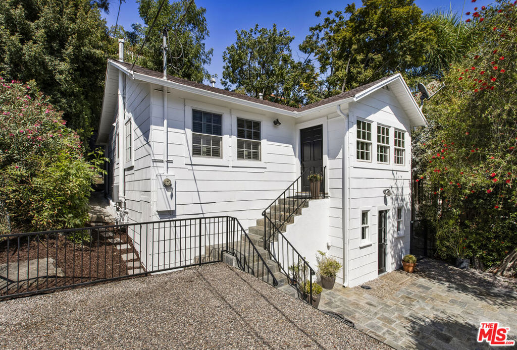 This timeless 1923 California bungalow is tucked behind gates and introduced by slate steps leading to a private front courtyard shaded by lush, mature palms. Situated at the base of Franklin Hills and perched slightly above the street, this lovely home has been completely reimagined from top to bottom by an interior designer, blending earthy, authentic charm with elegant, modern finishes. Inside, a vaulted entry anchored by a striking Flos pendant fills the main living space with natural light, while front windows frame a vibrant bottlebrush tree currently bursting with red blooms. The chef's kitchen is tastefully appointed with a farmhouse sink, butcher-block counters, bespoke custom cabinetry, stainless steel appliances, and a Bertazzoni Italian range and hood. Two well-proportioned bedrooms, each with its own en suite bath, occupy the main level. The bathroom for the second bedroom is smartly designed to also open to the hallway for convenient guest access, and features Carrara marble tile. The second bedroom - currently enjoyed as an additional living space - connects to the living room through French doors. The primary suite is a retreat in itself, featuring a spa-like bath with dual sinks and a spacious shower with a 12-inch rain shower head, plus two closets flanking a set of French doors that open directly to your backyard sanctuary. The adjacent laundry/pantry area also provides convenient outdoor access. Together, these spaces create a seamless connection to your private oasis: a terraced yard that unfolds into layered outdoor rooms, including a wood deck perfect for dining al fresco, shaded nooks beneath graceful trees, lush ferns and seasonal blooms, and thoughtfully designed turf and pebble areas that are both calming and low-maintenance. A versatile bonus room with a third bathroom and separate entrance below offers flexible options for a home office, art studio, or guest suite. Throughout the home, Brazilian mahogany floors (reclaimed from Armani Exchange on the Westside) add warmth, while recessed lighting with dimmers, hardwired speakers, and thoughtfully updated fixtures bring a modern ease. All systems were updated in/around 2010, including copper plumbing, new wiring, a 200-amp panel, central air and heat, and dual-pane windows. More recent upgrades include foundation improvements, a tankless water heater, and freshly painted interior and exterior. Completing the property is a one-car detached motorized garage, tucked discreetly away yet easily accessible. Just two blocks from vibrant Sunset Junction favorites like Bar Stella, Intelligentsia, Pine&Crane, Tartine, Black Cat, The Win-Dow and Bacari Silverlake, and all the neighborhood destinations and conveniences on Hyperion like The Ceviche Project, Speranza, Mixto, What the Fish, Tenant in the Trees, Gelsons and Trader Joe's. A one-of-a-kind beauty, this is the home you've been waiting for.