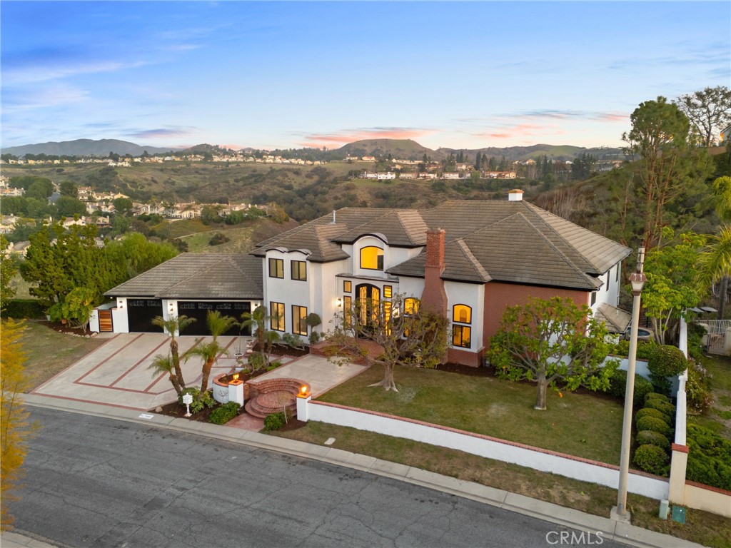 Welcome to an extraordinary estate in the prestigious Anaheim Hills, where timeless elegance meets modern luxury. This fully renovated masterpiece offers 4,480 sq. ft. of living space, featuring five bedrooms and four bathrooms, set on an expansive 28,800 sq. ft. lot with breathtaking city light and mountain views.
A grand entry with soaring ceilings, a striking staircase with black wrought-iron railings, and custom lighting sets the tone for sophistication. The open floor plan features engineered wood flooring, oversized windows, and a floor-to-ceiling fireplace, creating an inviting ambiance. The chef’s kitchen is a showpiece with a marble waterfall island, top-tier appliances, a custom range hood, and a six-burner stove. A spacious walk-in pantry offers ample storage.
The primary suite boasts a fireplace, balcony access, and a private spa, perfect for relaxing while taking in the stunning views. The en-suite bathroom features dual vanities and a soaking tub, with Italian slab porcelain stones in the Family Room and Master Suite for added luxury.
Each additional bedroom is generously sized, offering natural light and premium finishes. The bathrooms, fireplaces, and balconies are finished with elegant Spanish porcelain tiles, adding a timeless touch.
The backyard is a private oasis with a full outdoor kitchen, built-in BBQ, expansive seating areas, lounge areas, and outdoor porcelain tiles. This space is perfect for entertaining or relaxing under the stars.
This home is equipped with a smart home system, including 11 cameras for security and 32 speakers throughout, creating a fully integrated audio experience.
Located in one of Anaheim Hills’ most sought-after areas, this estate offers the perfect blend of luxury, comfort, and modern convenience. Schedule your private tour today! Don't forget to take a look at the virtual tour and supplements.