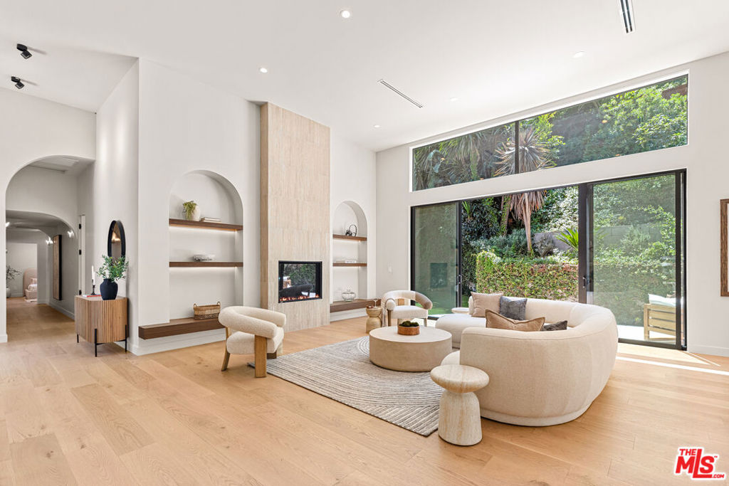 Located on a quiet street in one of Brentwood's most desirable pockets, this beautifully reimagined 4-bedroom, 6-bath modern residence offers the perfect blend of high-end design and everyday comfort. A dramatic 10-foot entry door sets the tone for the spacious interior, featuring soaring 14-foot ceilings, wide-plank hardwood floors, and seamless indoor-outdoor living. The open-concept layout includes a chef's kitchen with premium appliances, a generous dining area, and expansive living spaces framed by black aluminum sliding doors that open to a private backyard oasis with a newly built pool, spa, and alfresco dining area perfect for entertaining. The luxurious primary suite features a spa-style bath with dual vanities, a freestanding soaking tub, and a custom walk-in closet. Two elegant powder rooms, a newly added theater, and a large entertainment lounge with a fireplace enhance the home's livability and style. Additional upgrades include a fire-resistant standing seam metal roof, all-new electrical and plumbing systems, and a spacious 3-car garage with ample storage.
