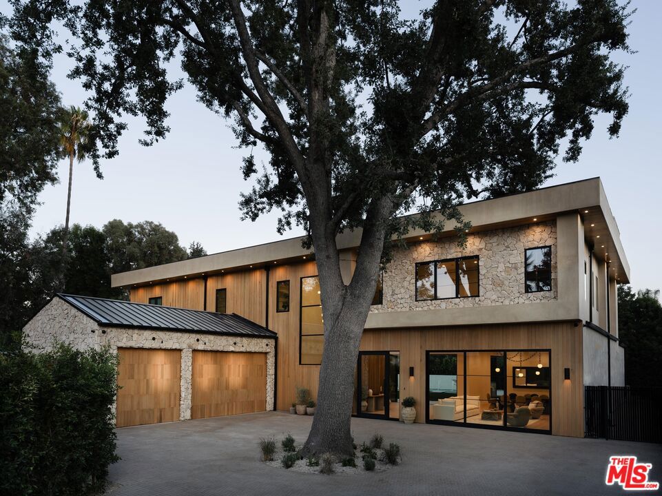 Introducing an extraordinary new construction nestled in the highly sought-after Walnut Acres enclave of Woodland Hills. This 5BD/6BA home is bathed in natural light and offers graceful transitions between indoor and outdoor spaces. Upon entry, a warm living area sets the tone, where a serene color palette and white oak floors flow effortlessly into the formal dining room, an ideal setting for both intimate dinners and lively gatherings. At the heart of the home, the sophisticated kitchen is outfitted with a La Cornue range, Thermador appliances, rustic white oak cabinetry, and a richly appointed butler's pantry designed for effortless entertaining. The adjoining family room opens directly to the kitchen and is anchored by built-in shelving and expansive floor-to-ceiling pocket doors, opening to the backyard for the ultimate California indoor-outdoor living. The first floor is completed by a guest en-suite, a private office, a theater room, and a stylish powder bath. Upstairs, the remarkable primary suite serves as a private sanctuary with soaring ceilings, two custom-designed walk-in closets, a decorative fireplace, and a tranquil balcony overlooking the grounds. The spa-like primary bath indulges with dual vanities, generous counter space, a soaking tub, an oversized walk-in shower with built-in bench, and a private water closet. The three additional bedrooms offer their own en-suite bath and abundant closet space. Just right off of the bedrooms, a beautifully outfitted laundry room with dual washer/dryers, extensive cabinetry, and a deep sink ensures both style and function. The grounds are an entertainer's dream, featuring a private pickleball/basketball court, sparkling pool with waterfall and spa, built-in barbecue, expansive lawn, and a sleek firepit with integrated seating. Additional highlights include a Control4 smart home system and a three-car garage with a gated driveway. Perfectly positioned minutes from award-winning El Camino Charter High School, the El Camino Shopping Center, and the premier boutiques and dining along Ventura Boulevard, this exceptional residence delivers modern sophistication and unmatched convenience in one of Woodland Hills' most sought-after neighborhoods.