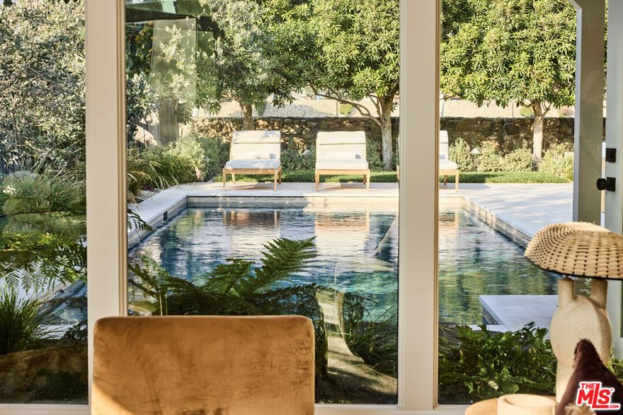 Tucked behind the guarded gates of the exclusive Malibu Colony, this reimagined mid-century modern masterpiece originally crafted by iconic architects Buff & Hensman embodies the essence of casual California living. Their signature blend of wood and glass architecture, which defined 1960s coastal style, lives on in this striking home, now thoughtfully elevated by award-winning architectural designer Warren Garrett. His vision honors the home's original design while introducing modern sophistication.Set beneath a canopy of mature sycamores, the residence is approached via a sandblasted limestone path that echoes the organic textures of the nearby shoreline. Inside, a dramatic open-concept layout unfolds across five bedrooms and five bathrooms, with soaring ceilings and a floating staircase wrapped in wide-plank white oak and framed by a floor-to-ceiling glass wall that invites in abundant natural light.The chef's kitchen is a sleek, functional centerpiece outfitted with Gaggenau appliances, minimalist cabinetry, and a spacious island perfect for culinary exploration or casual gatherings. Throughout, the home is outfitted with Universal Control4 automation and an integrated sound system, inside and out.The serene primary suite offers a private retreat, featuring a spa-inspired bathroom with honed limestone, white oak detailing, a hand-carved rigato stone bathing niche, private water closet, and dual custom closets. A secluded balcony reveals sweeping mountain and ocean views, creating a tranquil haven. Outdoor living is redefined in this secluded sanctuary, where a shimmering pool anchors the courtyard. The outdoor kitchen fully equipped with top-of-the-line appliances and generous seating sets the stage for unforgettable al fresco dining under the stars. Privately gated from the street with nearly 50 feet of frontage, this estate offers an unmatched sense of seclusion within the Colony. While just steps from your deeded, beautifully appointed beach access reserved for a select group of homeowners you can enjoy complete privacy and round-the-clock security. This rare offering captures the very best of Malibu Colony living: architectural significance, modern luxury, and the ultimate connection to land, sea, and sky.