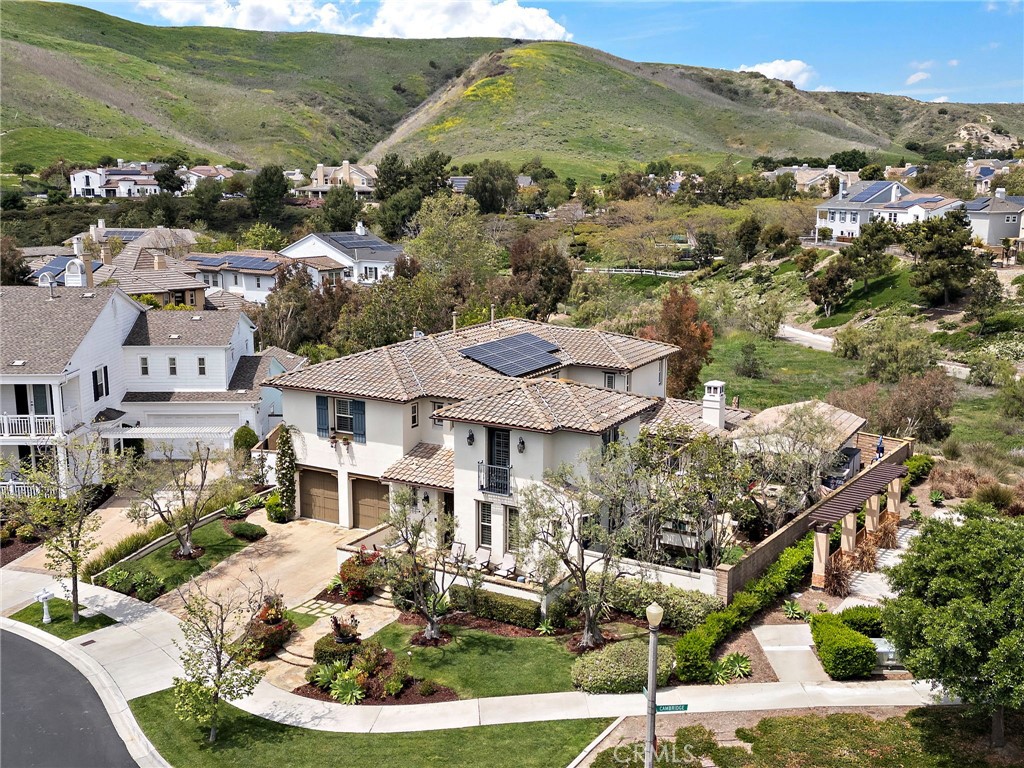 Located in the prestigious guard-gated Covenant Hills enclave of Ladera Ranch, this former model home in Montanez exemplifies luxury living. Practical updates include owned solar, recent whole house repipe, newer water heater, new water softener/filtration, outdoor kitchen loggia and your own private pool just in time for Summer! Set on a prime corner lot along a quiet cul-de-sac, the residence offers approximately 3,900 square feet of refined space, including 5 bedrooms and 4.5 bathrooms—with a convenient main-level guest suite. Thoughtfully designed for both comfort and style, the open floorplan is filled with natural light and features rich hardwood floors, custom woodwork and lighting, a family room with built-in media center and fireplace, and multiple French doors that seamlessly connect indoor and outdoor living.The remodeled chef’s kitchen is a standout, boasting dual islands with Calacatta marble countertops, high-end cabinetry, a sunny breakfast nook, and premium stainless steel appliances including a built-in refrigerator. Upstairs, the private primary suite is a serene retreat, complete with finished dual walk-in closets, a spa-inspired shower, and a jetted soaking tub. Enjoy resort-style living in your own backyard oasis with pool, spa, central courtyard, and multiple entertaining spaces. A stunning outdoor loggia is equipped with a stone fireplace, built-in BBQ, and a full gourmet kitchen—perfect for year-round entertaining. Built to impress, this model home showcases custom upgrades, professional design, and one of the best locations in the neighborhood. Walk to several neighborhood amenities including the red bucket water park, skate park, frisbee golf course, several pools, walking trails and local award winning schools. Don’t Wait!