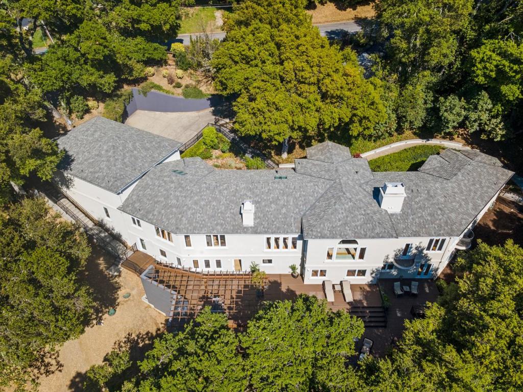 Tucked away on approximately 2.77 acres in the Vista Verde community with easy access to the amenities of Portola Valley, this remarkable property offers a peaceful retreat from the fast-paced life of Silicon Valley. A sweeping tiled stairway descends through lushly planted gardens to the main entrance, where the home opens to grand yet understated interiors that echo the serenity and refinement of the grounds. Enter the expansive main level with its 10 and 12 foot ceilings, including a spacious kitchen and family room combination with a large pantry for entertaining; adjoining dining and living rooms with arch-top windows that capture the stunning wooded views; and an elegant primary suite with dual exterior balconies, sitting area with fireplace, spacious walk-in closet, and a luxurious marble bath all enhanced by fine millwork, solid oak hardwood floors, and recessed lighting. The multi-functional lower level features two additional bedrooms one en suite a home office, an artist studio or home gym, and a large recreation room that opens to a massive, multi-level deck and pergola with a linear natural gas fire pit and a built-in kitchen barbecue area, creating an adjoining indoor-outdoor entertainment space that overlooks the private rear grounds.