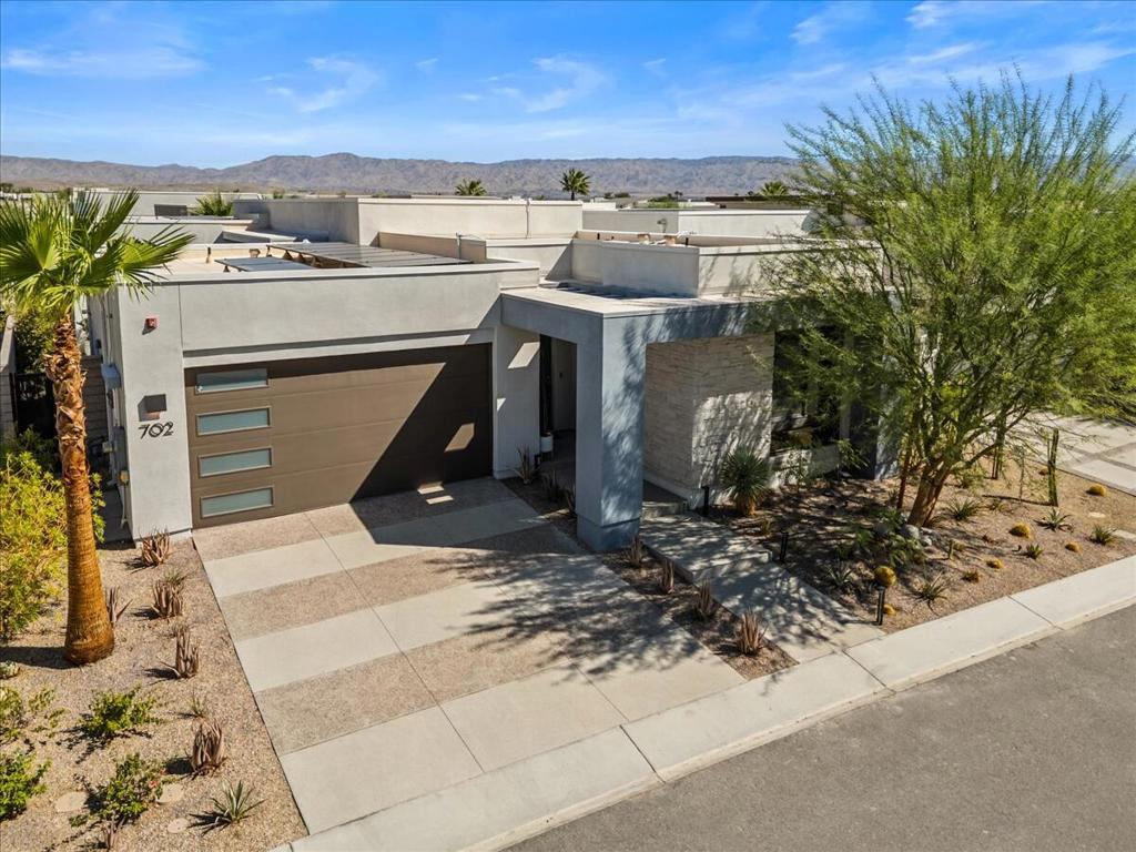 Welcome to 702 Fountain Dr: a one-of-a-kind 3BD/3.5BA home in the gated Miralon community, where mid-century modern flair meets resort-style living. This fully-furnished, turn-key Model Aura Residence 2B spans 2,084 sq ft and sits on a 5,662 sq ft lot.Every inch of this home has personality imbued by its Disney designer owner: from the custom peacock and panther wallpaper to the modern abstract desert hallway mural and a bedroom/office outfitted as a recording studio. The sleek kitchen features a tempered glass and bespoke backsplash, updated hardware, and a reverse osmosis water system. The dramatic ''Jungle Room'' primary suite includes an upgraded sliding door that opens to the private backyard, and the great room features a sliding glass wall with views of the mountains and access to the pool.Energy-efficient and tech-forward, the home features solar panels with two Tesla Powerwall batteries, whole house water softener and filter system, zoned HVAC with smartphone control, as well as smartphone controlled garage door opener and front door lock, front door and other cameras, automatic window shades, and a full-home sound system.Outside, enjoy your own pool, gas fire feature, wood-fired pizza oven, luxury outdoor sectional and tranquil landscaping with palms, a fountain, and added privacy from the lot's easement distance from your neighbors. The front door faces South, a thoughtful detail for those who appreciate orientation and natural light flow.Located in highly desirable Miralon, the community offers miles of walking trails, olive groves with over 7000 trees, a you-pick herb and vegetable garden, clubhouse with cafe and bar, well-appointed fitness center, and for bicyclists nearby access to the new CV Link, as well as breathtaking mountain views -- desert living at its coolest.