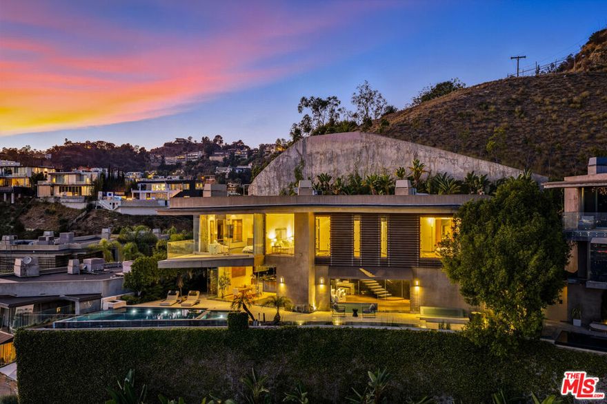 Experience Hollywood Hills living at its finest in this spectacular view property where luxury meets excitement. Sitting behind imposing 12-foot gates, the home is nestled in an exclusive, gated community consisting of only 5 additional residences. This contemporary showpiece boasts  3 bedrooms, 5 bathrooms, and breathtaking views from almost every window. The first floor is an entertainer's paradise, featuring a sleek bar and your very own home theater; perfect for lively gatherings or cozy movie nights. Ascend to the second level, where open-concept living and dining areas seamlessly blend into a chef's dream kitchen, fully equipped with top-tier appliances and designer finishes. Anchoring the heart of the home is an architecturally stunning floating staircase, guiding you to the upper floors. The primary suite is a true retreat: a lavish bedroom, spa-inspired bathroom, and an oversized walk-in closet await. Two additional bedrooms and a convenient upstairs laundry room complete the third level, ensuring space and comfort for all. Step outside and prepare to be amazedpanoramic views of the city stretch for miles, creating a breathtaking backdrop for relaxation or entertaining. This is more than a home; it's an invitation to live boldly and beautifully in the Hollywood Hills.