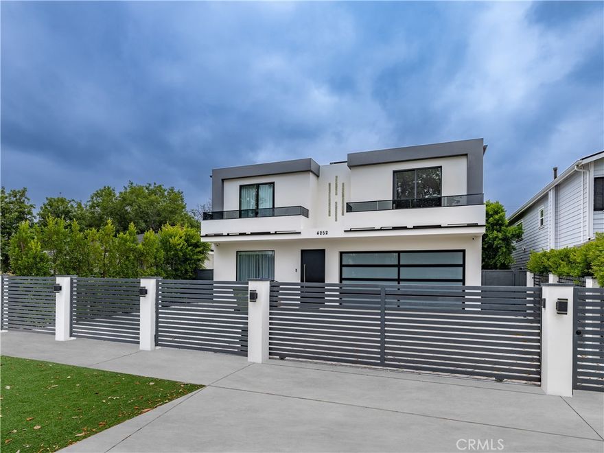 A rare opportunity to lease a gated, newly constructed modern estate in the heart of Studio City. This striking architectural residence offers five en-suite bedrooms, five and a half bathrooms, and over 3,700 square feet of thoughtfully designed living space. From the moment you step inside, you're welcomed by soaring ceilings, oversized porcelain tile floors, LED-lit architectural detailing, and walls of glass that flood the home with natural light. The expansive open-concept layout flows effortlessly from the elegant living room with a sleek linear fireplace to the showstopping chef's kitchen equipped with quartz waterfall countertops, two-tone high-gloss cabinetry, top-of-the-line integrated appliances, and a massive center island perfect for entertaining. Fleetwood-style glass sliders create seamless indoor-outdoor integration and open to a resort-style backyard sanctuary. Lush privacy hedging surrounds the space, where a sparkling zero-edge pool with Baja shelf, spa, multiple shaded lounge areas, and built-in BBQ create the ultimate setting for relaxation and entertaining. One bedroom suite is conveniently located on the main level, ideal for guests or use as a home office. Upstairs, the luxurious primary suite features a private balcony, spa-like bathroom with freestanding soaking tub, oversized rain shower, and dual vanities, as well as a boutique-style walk-in closet with custom glass cabinetry and center island. Additional highlights include a designer powder room, upstairs laundry room, smart home wiring with surround sound and security cameras, zoned HVAC, and a fully finished two-car garage with frosted glass door and checkerboard flooring. Perfectly positioned on a quiet residential street just moments from Ventura Boulevard's premier shopping, dining, and entertainment, and with easy access to top-rated schools and major studios, this home offers the ultimate blend of modern luxury, comfort, and convenience. Now available for immediate lease.