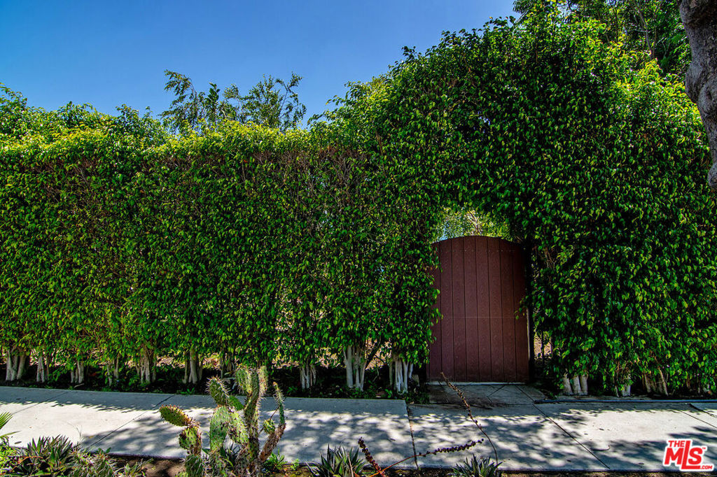 Welcome to this fully hedged and gated single-family home featuring 2 bedrooms and 3 bathrooms. Bright and inviting, the open-concept layout offers a sun-drenched living room complete with a custom coat closet and decorative fireplace. The standout kitchen showcases elegant Carrera marble countertops, stainless steel appliances, and a charming breakfast bar that flows seamlessly into the dining and living areas. The spacious primary suite includes a dedicated office or sitting area, custom closet, direct access to the backyard through French doors, and a stylish en-suite bathroom with a walk-in shower. The second bedroom offers a generous walk-in closet and tranquil views of the lush front yard. Step outside to your private backyard retreat, featuring mature landscaping, fruit trees, and plenty of space to relax or entertain. A converted garage provides a versatile bonus space with a full bathroom and above-ground spa. Additional features include two driveway parking spaces, central AC/heat, hardwood floors, recessed lighting, and in-unit washer and dryer. Just moments from Melrose's premier shopping, dining, and entertainment!!