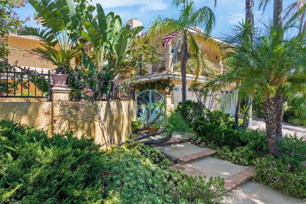 This Mediterranean-style home, with its distinctive Mid-Century Modern flair, presents a rare opportunity for a buyer with vision. Situated on a desirable corner lot within a highly sought-after top-tier school district, the property features a private, gated entry. Inside, soaring ceilings, an elegant MCM staircase, and an impressive floor-to-ceiling fireplace are complemented by expansive windows that fill the sunken living and dining areas with natural light. The main level offers a flexible bedroom and a full bath, alongside a spacious den that could function as a sixth bedroom or combine to create a private mother-in-law suite or attached rental apartment. Stone flooring in the living and dining rooms leads to a covered patio and a lush, tropical-style garden featuring a Koi pond, lap pool, and two covered patios. An eat-in kitchen with sliding doors opens to a second covered patio with stone tile and a unique aviary. A three-car garage provides ample storage. The second floor features an extra-large primary bedroom with a huge private balcony, fireplace, and two closets, including a walk-in, plus a massive en-suite bath. Three additional generously sized bedrooms, two with their own balconies, and extensive storage complete the upstairs. This home is a canvas awaiting your creative vision.