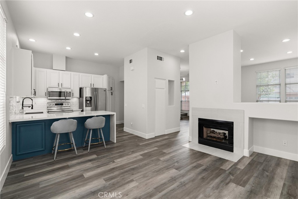 Welcome to the largest floor plan available in the highly sought-after, quiet, and gated Summit Renaissance Community. This end-unit townhome has been thoughtfully upgraded throughout, offering both style and functionality. Step inside through a smart front door lock into a bright and open main living area featuring luxury vinyl plank flooring, 5-inch baseboards, fresh paint, and a stunning remodeled dual-sided fireplace. The layout seamlessly connects the den, dining area, family room, and kitchen—ideal for modern living and entertaining. The remodeled kitchen showcases a sleek waterfall-edge quartz countertop, a full subway tile backsplash, and stainless steel appliances. Custom-finished cabinetry includes matte black hardware and soft-close mechanisms, complemented by a large farmhouse sink for both beauty and utility. Just off the kitchen is a stylishly upgraded half-bathroom and direct access to the attached two-car garage. A whole-home water filtration system ensures clean, treated water throughout every tap in the house—perfect for healthy living, soft water, and peace of mind. Upstairs, you’ll find a completely carpet-free second level. The expansive primary suite is a standout, featuring both a walk-in and sliding closet, and a beautifully remodeled en-suite bathroom. The upgraded shower features sleek tile work, modern black fixtures, and a seamless glass enclosure. Dual sinks are set in an expansive quartz slab, complemented by elegant ceramic tile flooring and coordinated cabinetry. Two additional bedrooms share a convenient Jack-and-Jill bathroom, ideal for families or guests. Located within the prestigious Orange Unified school district and nestled in a peaceful, gated community, this smart, clean, and sophisticated home offers upscale living in one of Orange County’s most desirable neighborhoods.