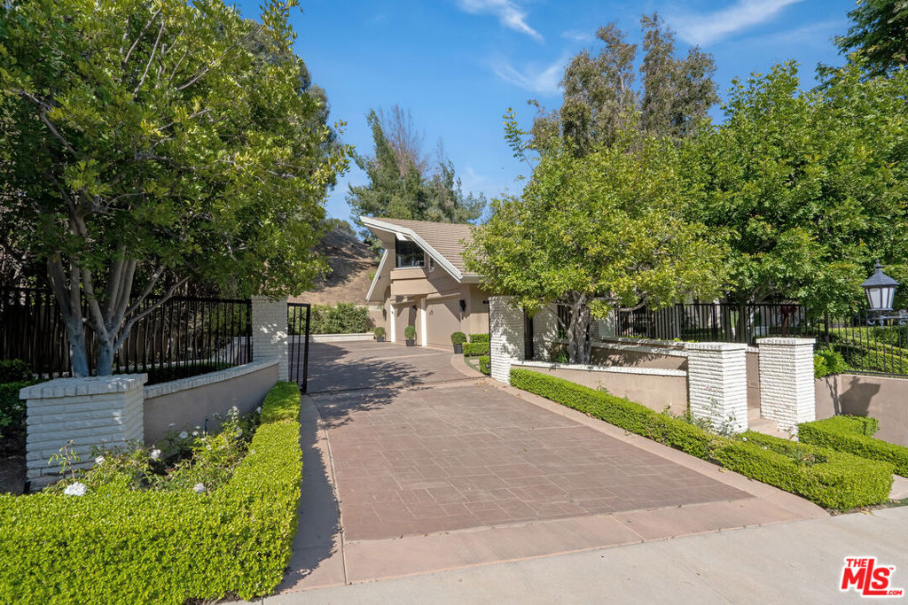 Set within the prestigious gated Colony of the Royal Oaks of Encino, this one-of-a-kind Mid-Century masterpiece sprawls across nearly two acres of lush greenery. It boasts approximately 8,000 square feet of living space, with four bedrooms, seven and a half bathrooms, and several other oversized living spaces. Upon entering through the dramatic double front door, soaring double-height ceilings and stunning angular architecture sets a precedence for what's to come. The main level encompasses formal and informal dining, multiple living rooms with fireplaces, and a gourmet Chef's kitchen with a large stone-topped island, white bespoke cabinetry, top-of-the-line appliances, and a cozy breakfast nook flanked with large windows and glass doors that open up to the private backyard oasis. The upper level is home to the spacious primary suite, complete with a private kitchenette, fireplace, wood beams, and a spa-like bathroom that features dual vanities, a sunken tub with jets, and a vanity. 2 Additional sun-filled en-suite guest bedrooms can also be found on this level and are separated by a large home gym. The exterior of the property is perfect for entertaining, featuring a large pool, spa, gazebo, and gracious grass area. And of course, the private tennis court and cabana is an excellent supplement. Only minutes from the famed Ventura Boulevard, where you can find the finest shops and restaurants, this property is an Encino gem! It is offered fully furnished and is sure to make for a one-of-a-kind experience.