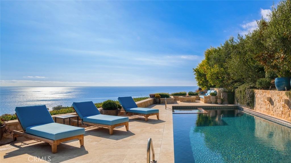 Discover unparalleled luxury in this exquisite French Country-style estate crafted by renowned builder Paul Brant Williger and featured in Luxe Magazine and two HBO productions. Nestled in a prestigious enclave (soon to be part of a gated, fire-wise community) this architectural gem blends breathtaking ocean views over Little Dume, with world-class amenities and impeccable craftsmanship. A stone-arched entryway invites you into a world of sophistication and timeless grandeur, as you are greeted with soaring vaulted ceilings, reclaimed French oak floors, and antique wood beams. The living room is anchored by a French antique wood-burning fireplace that seamlessly connects to the outdoors. The adjacent great room charms with a cozy firewood nook. The chef's kitchen is a culinary masterpiece featuring a sprawling quartzite island, Caesarstone counters, and premium appliances (6-burner Wolf range, Wolf microwave, Miele dual dishwashers, Sub-Zero refrigeration to name a few). The formal dining room captivates with a fireplace, wood-beamed vaulted ceilings, French tiles, and sweeping coastline vistas. A nearby powder room impresses with French tile floors, floating sink imported from France, and bespoke lighting. The primary suite offers ocean and pool views, a vaulted ceiling, walk-in closets, and fireplace, and sliding doors to the lush backyard. Its spa-inspired ensuite boasts mosaic tile floors, stone counters, double vanity, walk-in shower with a marble bench, and an in-ground soaking tub framed by elegant French windows. A converted garage serves as a versatile office or gym, complete with skylights, and French doors opening to the garden. The laundry room includes built-in storage, washer and dryer, and a wine fridge. The backyard is a private paradise, showcasing panoramic ocean views, a rectangular pool with an integrated hot tub, a fire pit with a custom-built couch, and a tranquil waterfall. A covered outdoor dining area, equipped with infrared heaters and an exterior fireplace, ensures year-round enjoyment. Hand-finished French slip-resistant limestone elegantly paves the yard. Uncompromising craftsmanship defines this estate, from imported antique doors to a handmade Tuscan tile roof. Modern conveniences include ultra-sound-resistant glass windows and sliders, push-button automatic shades, a whole-home generator, three-zone climate control, and a comprehensive security system.