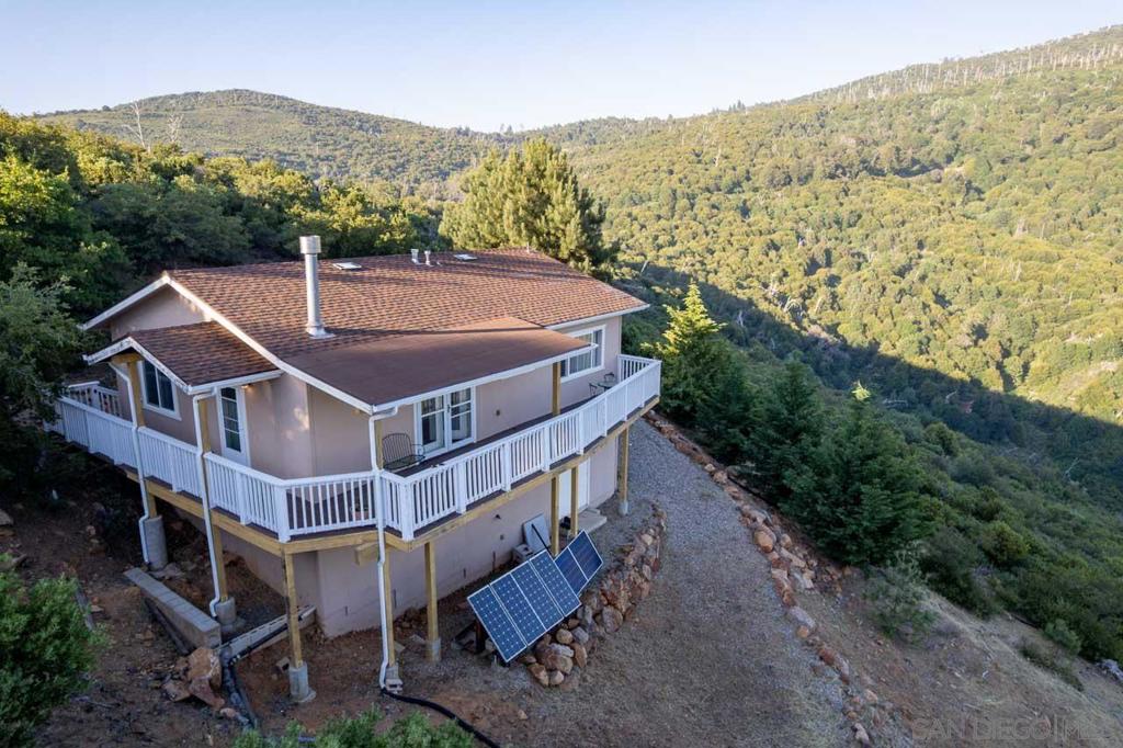 Take a drive past a picturesque lake and up a mountain to a hidden road guarded by an electronic gate. High Hill is like no other off-grid road, with unparalleled views and breathtaking splendor. This home sits on the edge of a hill, surrounded by pine, manzanita, and cedar trees, and seems to float between the peaks. Cuyamaca Woods is an off-grid community with several sections all nestled onto the ridges and bluffs of North Peak in Julian. The High Hill cabin is a well-designed, comfortable, and thoughtfully built 2-bedroom 2-bath home. The home is heated by a Propane wall heater and a wood stove. Cooling winds are frequent each season, and convenient ceiling fans for more circulation on warm days. Step out onto the spacious deck that runs the length of the home and wraps to the entry. Spend time watching graceful hawks glide and hearing the wind through the pines. The full kitchen has a view into the canyon, plenty of storage, and all the amenities to cook up a gourmet dinner for every season. The important details to make mountain life comfortable have been added with owned solar power, a 12,000-watt generator for backup, a private well and 5,000-gallon water tank, as well as a large under-house storage area. *The known Fees associated with this community are through the Cuyamaca Fire Safe Council. *A non-mandatory suggested annual contribution of $125 goes towards maintaining gates and roads.